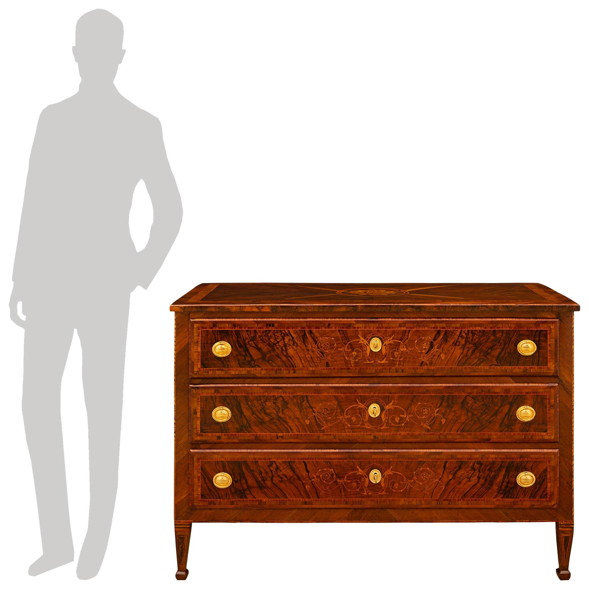 A handsome and wonderfully designed pair of Italian 18th century Louis XVI period Walnut and Ormolu commodes. Each stunning commode with all of its original hardware is raised by four square tapered legs decorated by triangular Burl Walnut inlays on