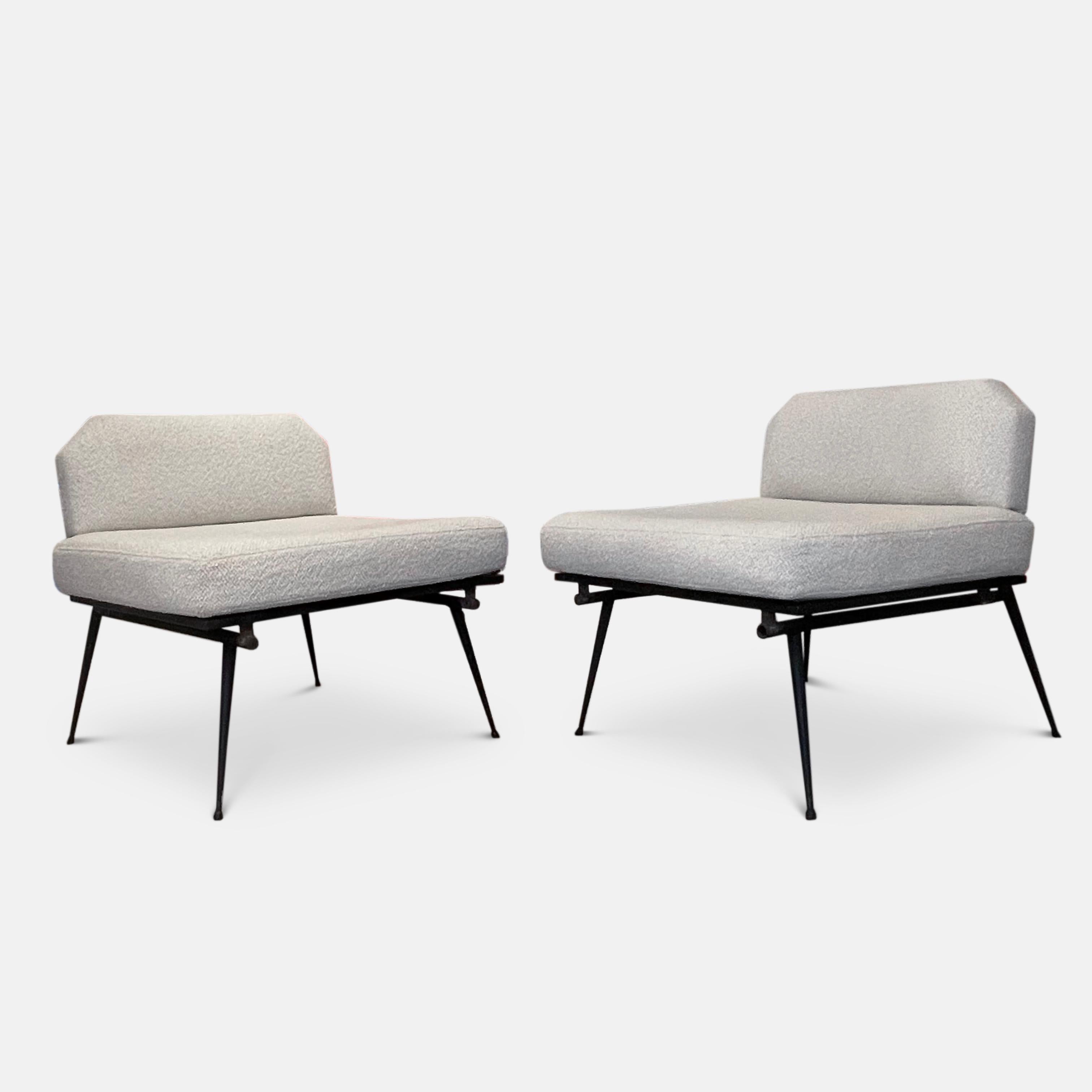 A stunning pair of Italian 1950s low lounge chairs in the manner of Studio bbpr. 
Constructed on a minimal metal base with splayed tapering legs and decoratively angled back supports, this pair of chairs has been newly upholstered in a Dedar Boucle