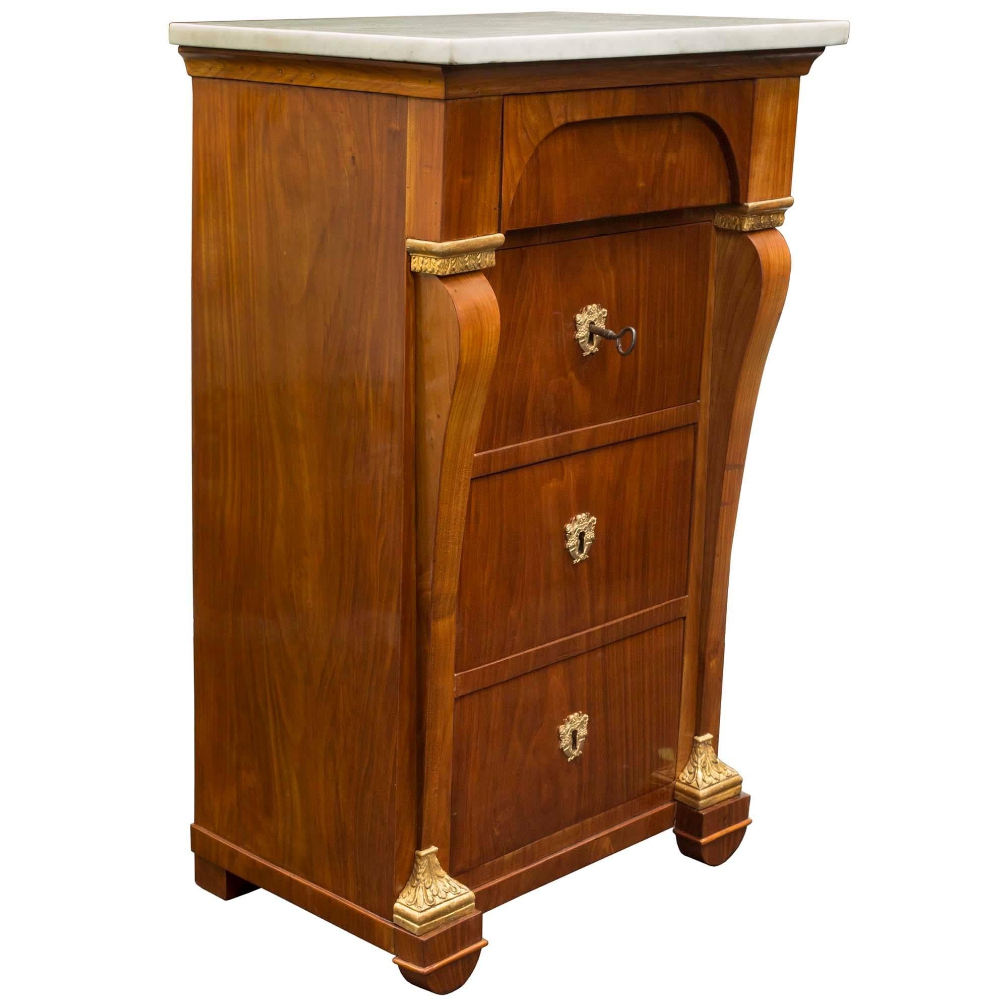 A most handsome and unique pair of Italian 19th century neoclassical style marble, ormolu, giltwood and cherrywood chests or side tables. Each chest, which can also be used as bedside tables, are raised by rounded feet below richly carved giltwood