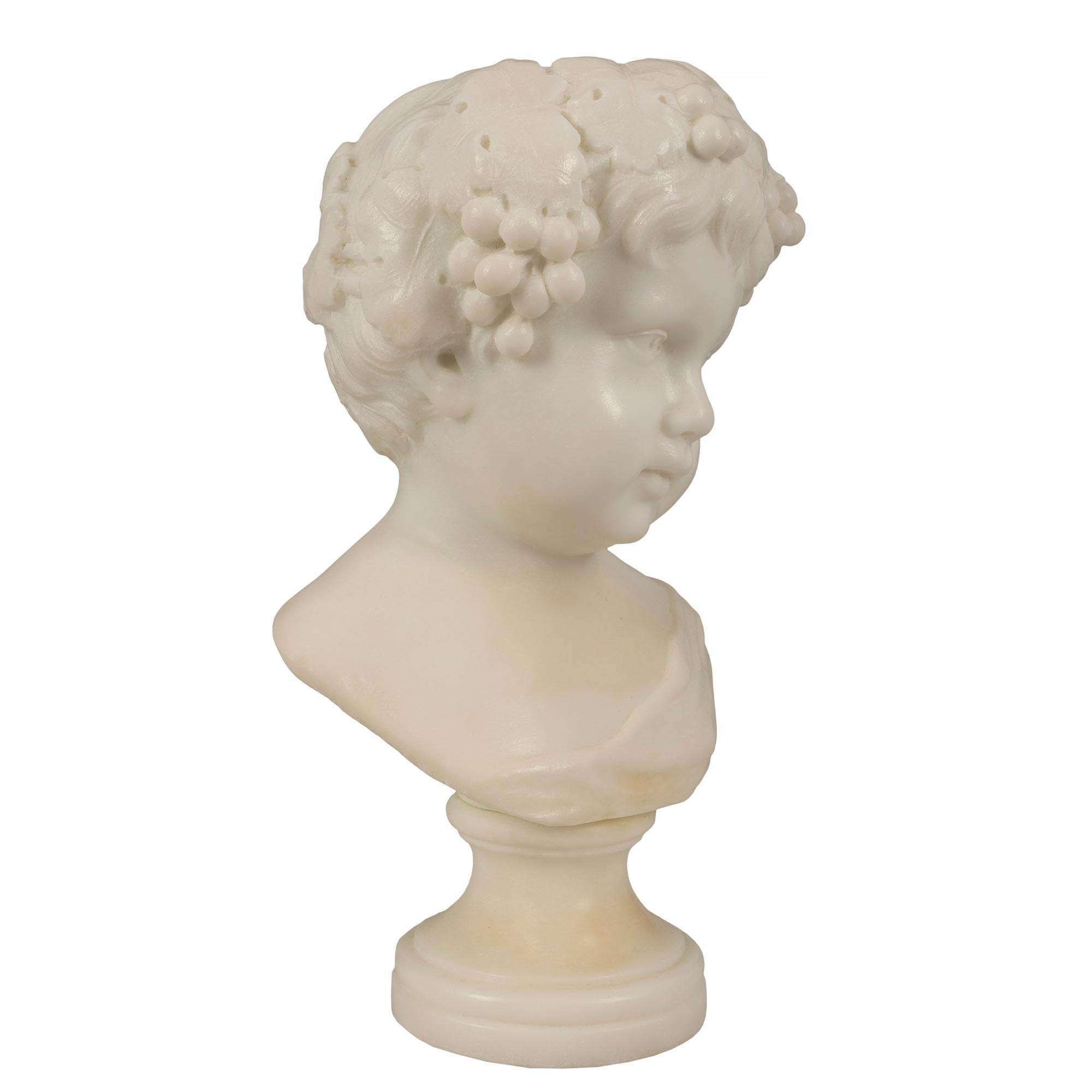 A charming pair of Italian 19th century white Carrara marble bust of young Bacchus. Each bust is raised by circular socle pedestals. With wonderful smiling expressions and a crown of grape clusters in their hair. Extremely decorative.

