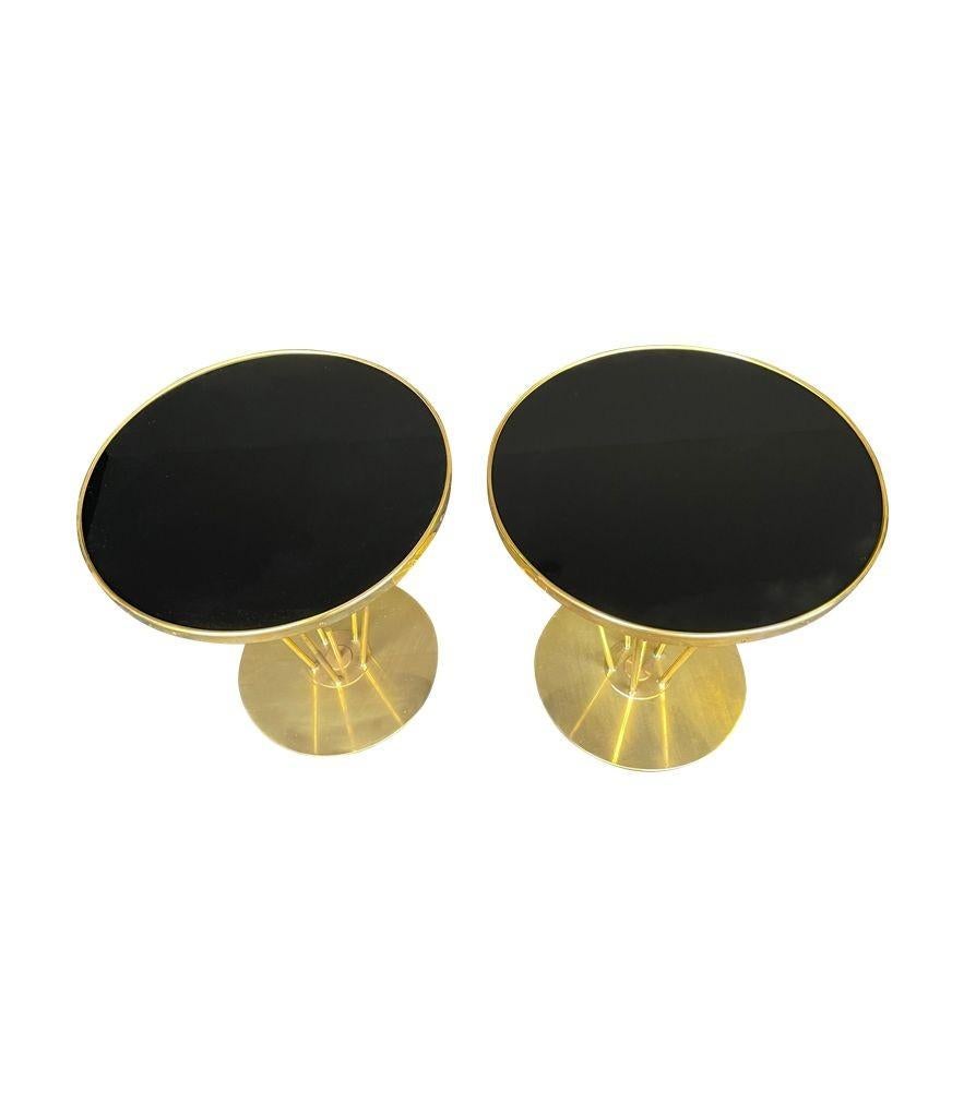 A pair of Italian brass and black glass circular side tables with five central legs.