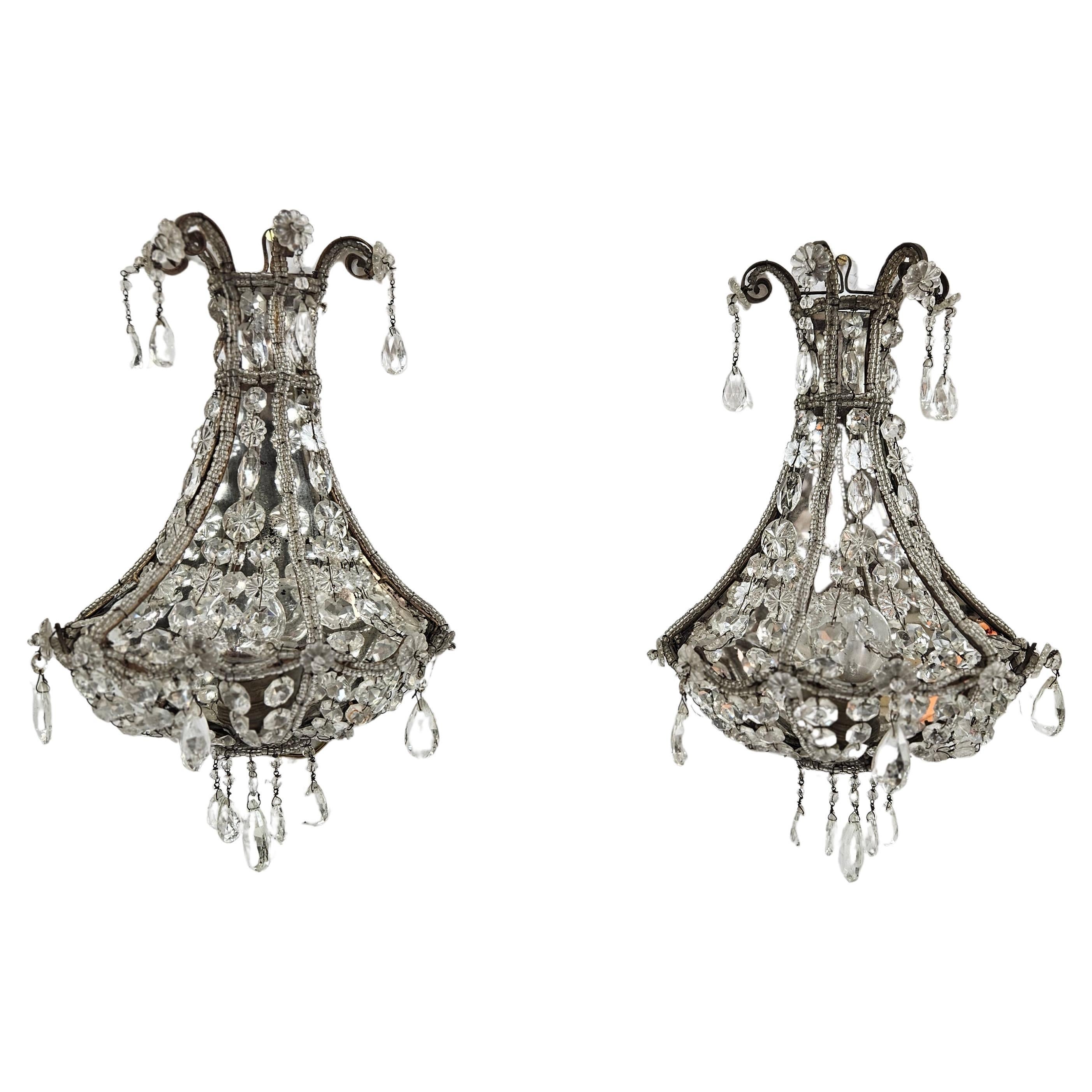 A beautiful pair of wall sconces produced in Italy during the 1940's. The style is romantic rococo with a beautiful classic design. Each sconce is adorned with clear crystals and glass beads. The light is reflected by a mirrored backside making