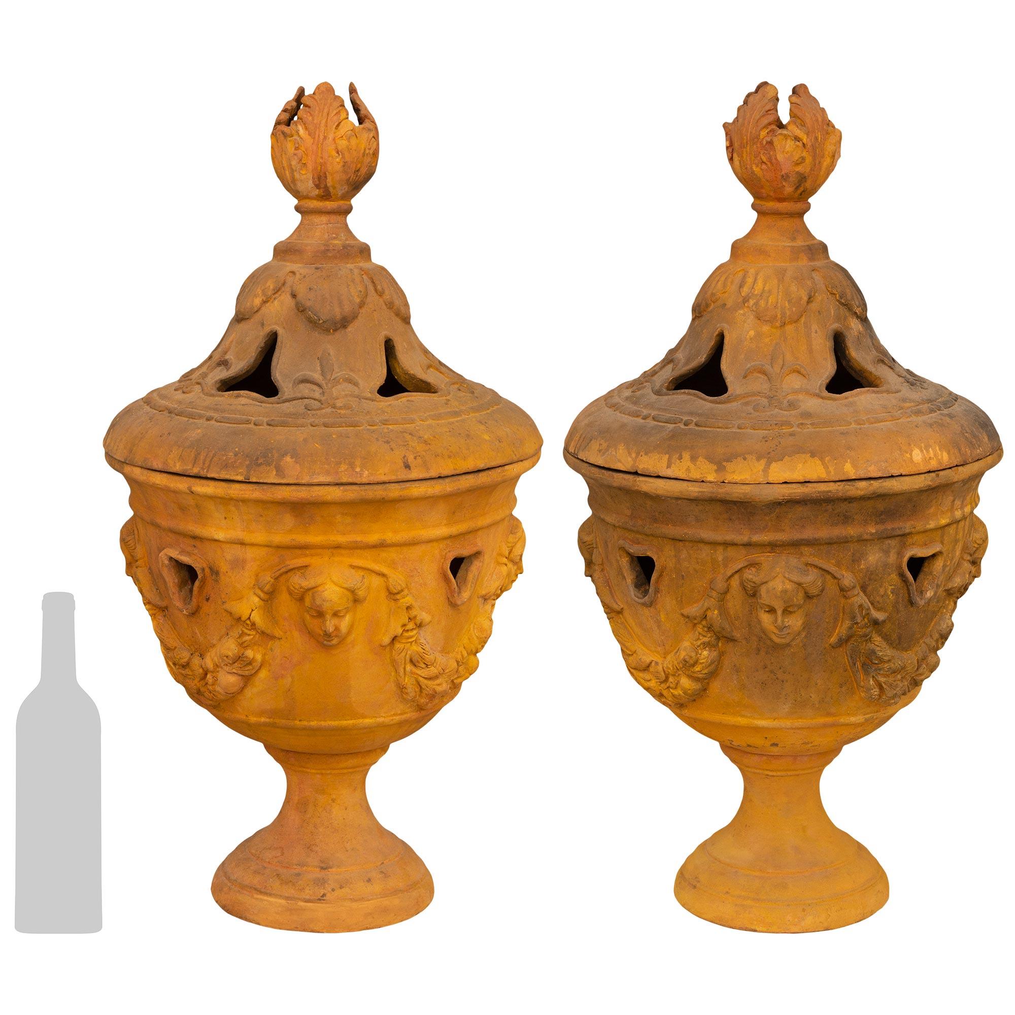 Magnifique paire d'urnes italiennes en terre cuite de style Louis XVI du début du XIXe siècle, finement détaillées. Chaque jolie urne de Toscane est posée sur une base circulaire en forme de socle aux bords marbrés. Le corps arrondi et percé est