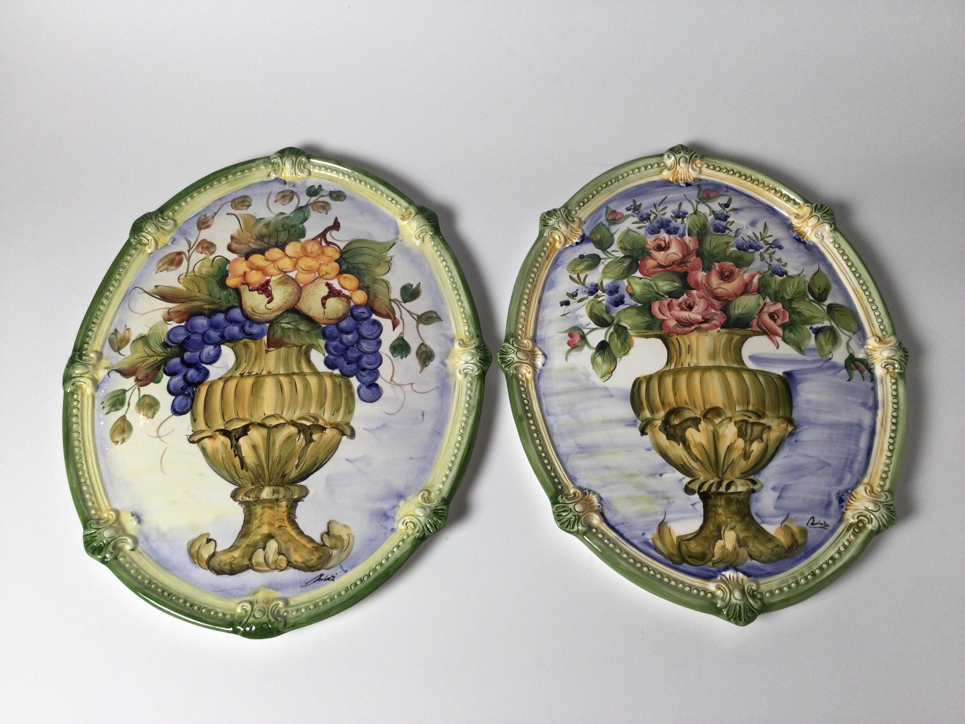 Vibrant pair of hand painted Italian Faience oval wall plaques. The textured borders with central urn and floral decoration. Made in Italy, Late 20th century.