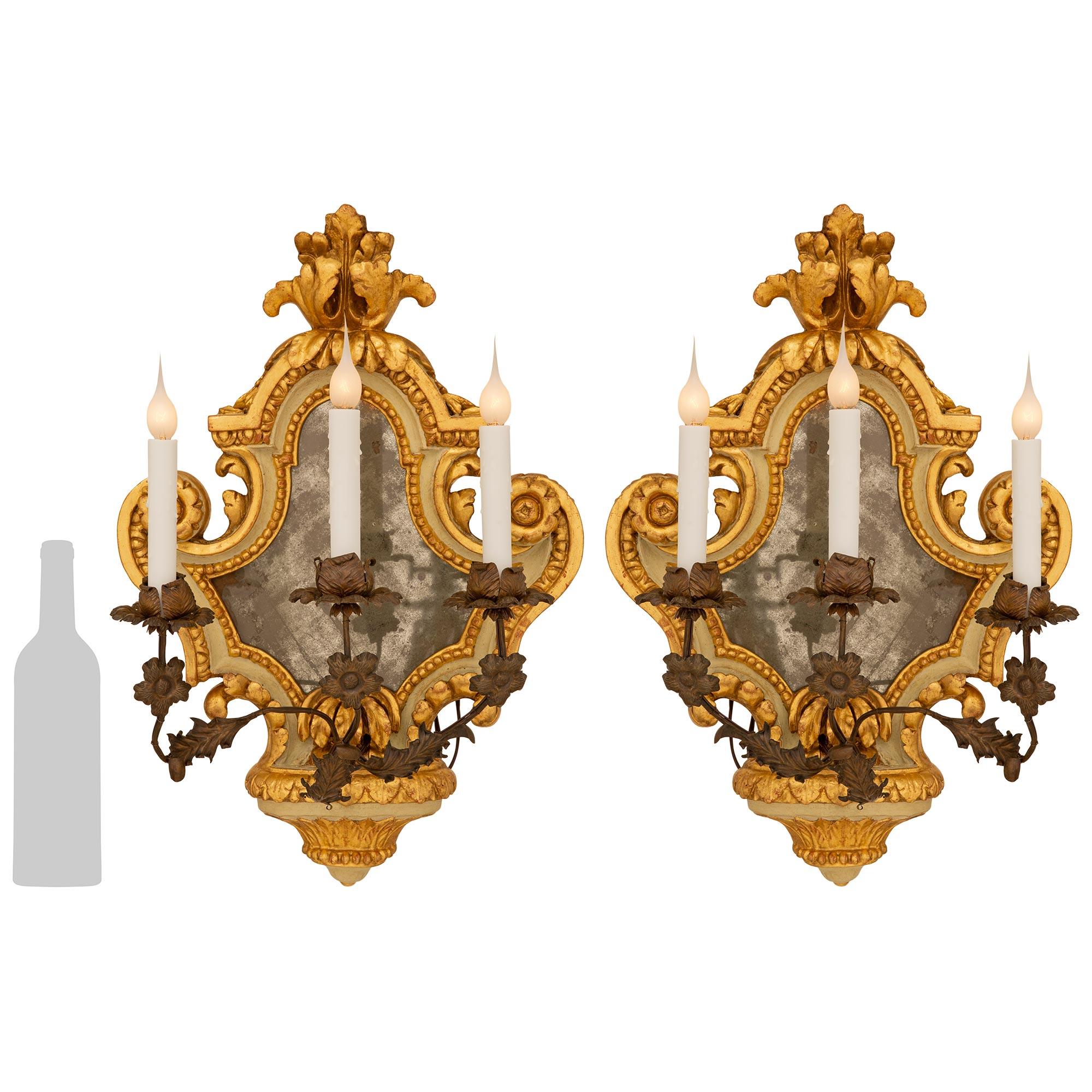Très belle paire d'appliques baroques italiennes de la fin du XIXe siècle en bois doré, bois patiné et métal pressé. Chaque applique de forme magnifique a conservé sa plaque de miroir d'origine sertie de motifs feuillagés sculptés très décoratifs et