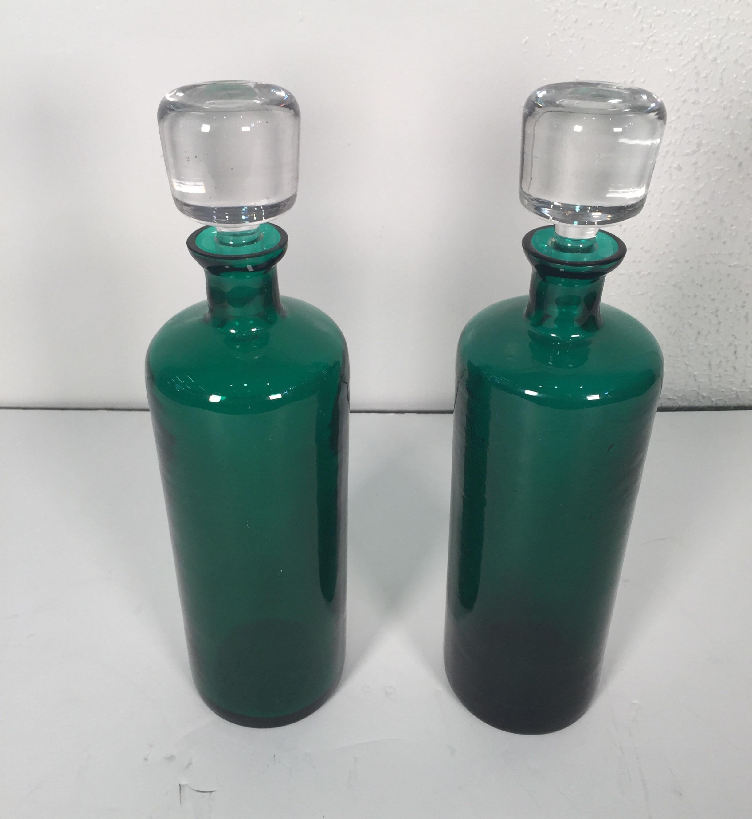 A pair of Mid-Century Modern emerald green decanters having clear original stoppers. One having the remnants of the Italian label.