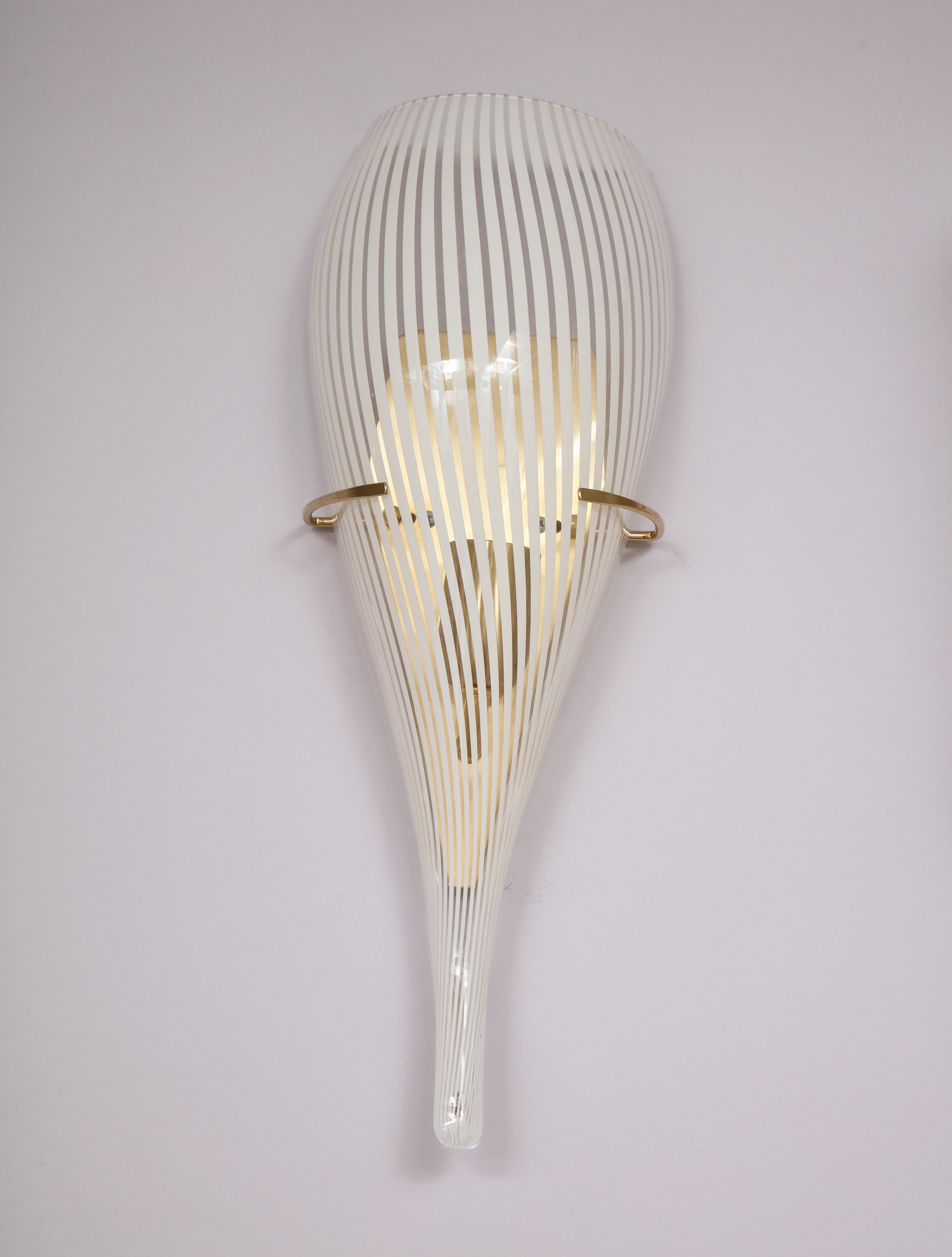 A pair of Italian Murano glass white and clear striped opaline wall sconces, of elongated conical shape; supported by triangular brass wall plaques with elegant ring holders on the face.
Italy, circa 1960
Size: 19