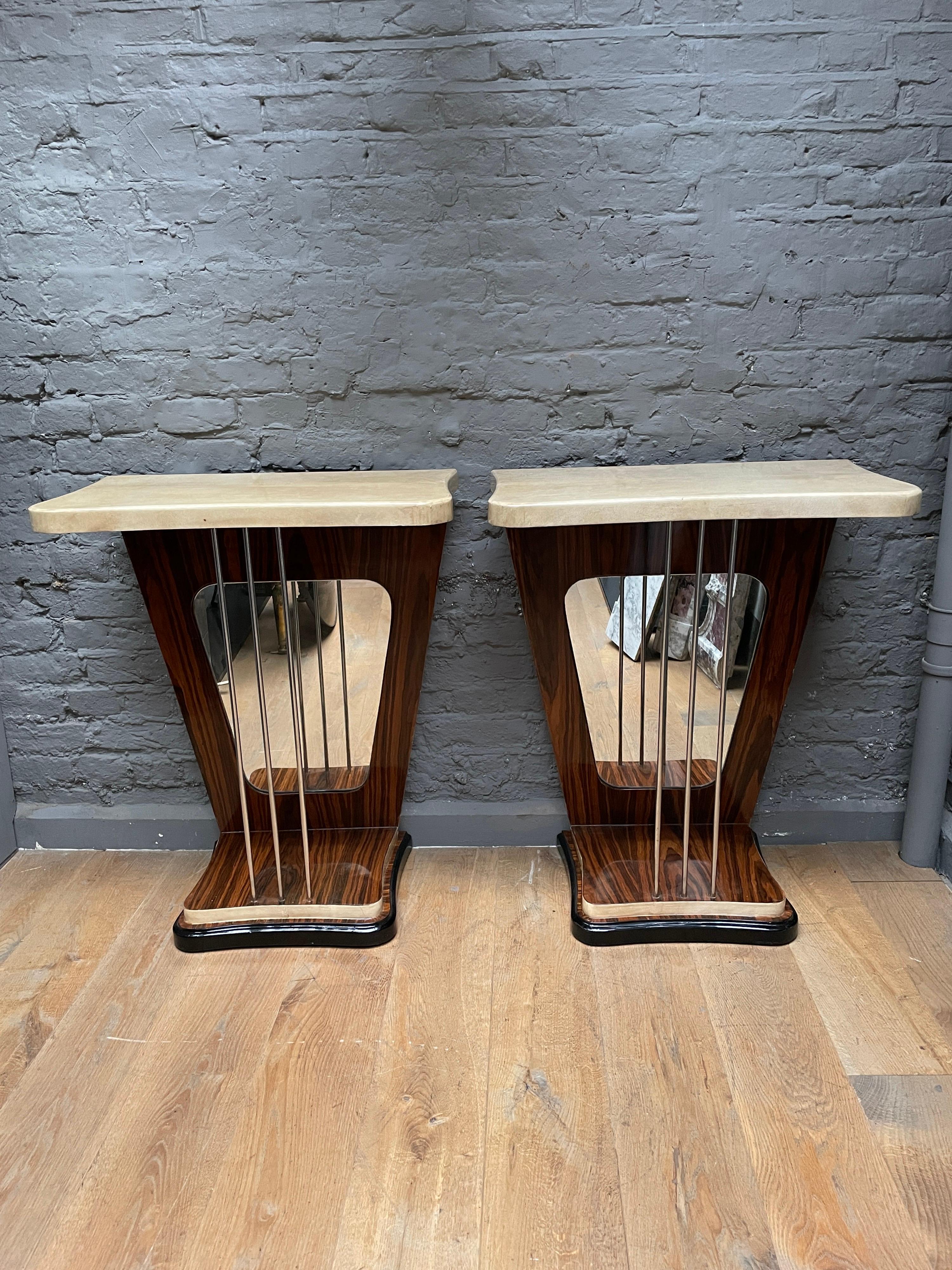 A pair of console tables with cream lacquered goatskin tops and edges, Palasander uprights and feet supported on an ebonized base. The shaped mirror inserts with supporting bars from base to top. A very stylised and typically Italian 50's pair of