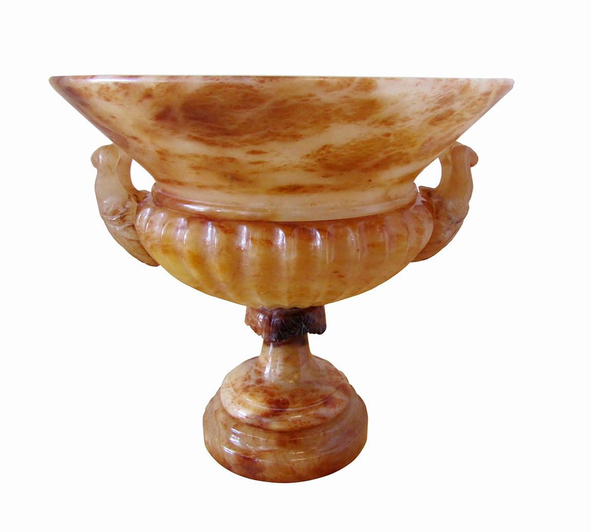 Pair Italian neoclassic onyx urns, the body flaring out with fluted bottom and highly carved and decorated handles, on a stepped base.