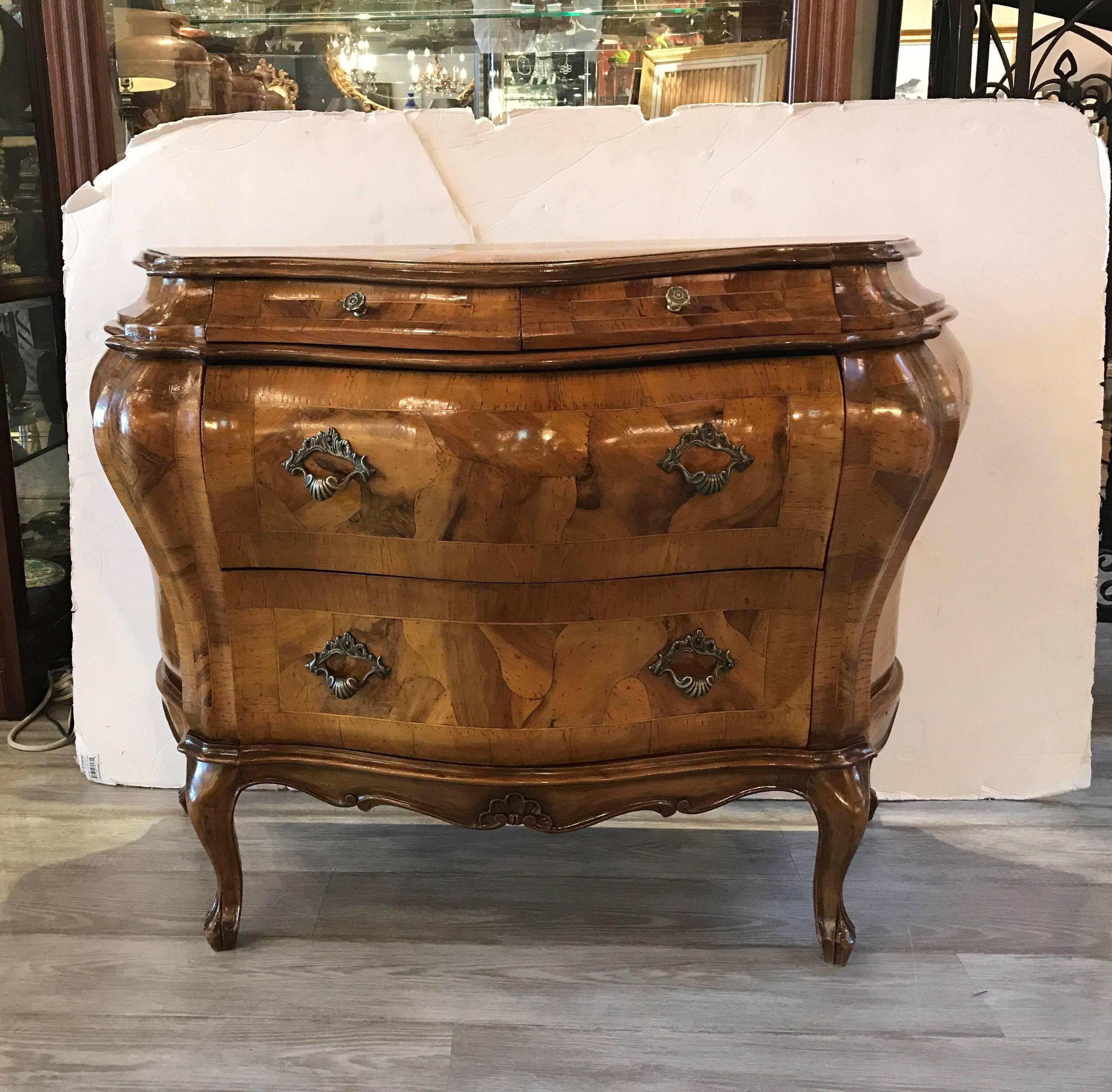 A shapely pair of mid-20th century Italian olive wood bombe form commodes. Two small drawers above two larger drawers resting on cabriole legs. The wood is a highly figurative olive wood in a tortoise shell pattern. The finish has a recent French