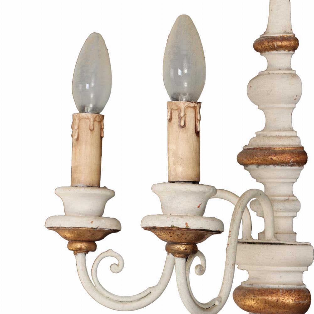 Cada una en marfil y oro, con un estandarte central torneado que sostiene dos candelabros de metal con volutas. También está disponible la lámpara de araña a juego.