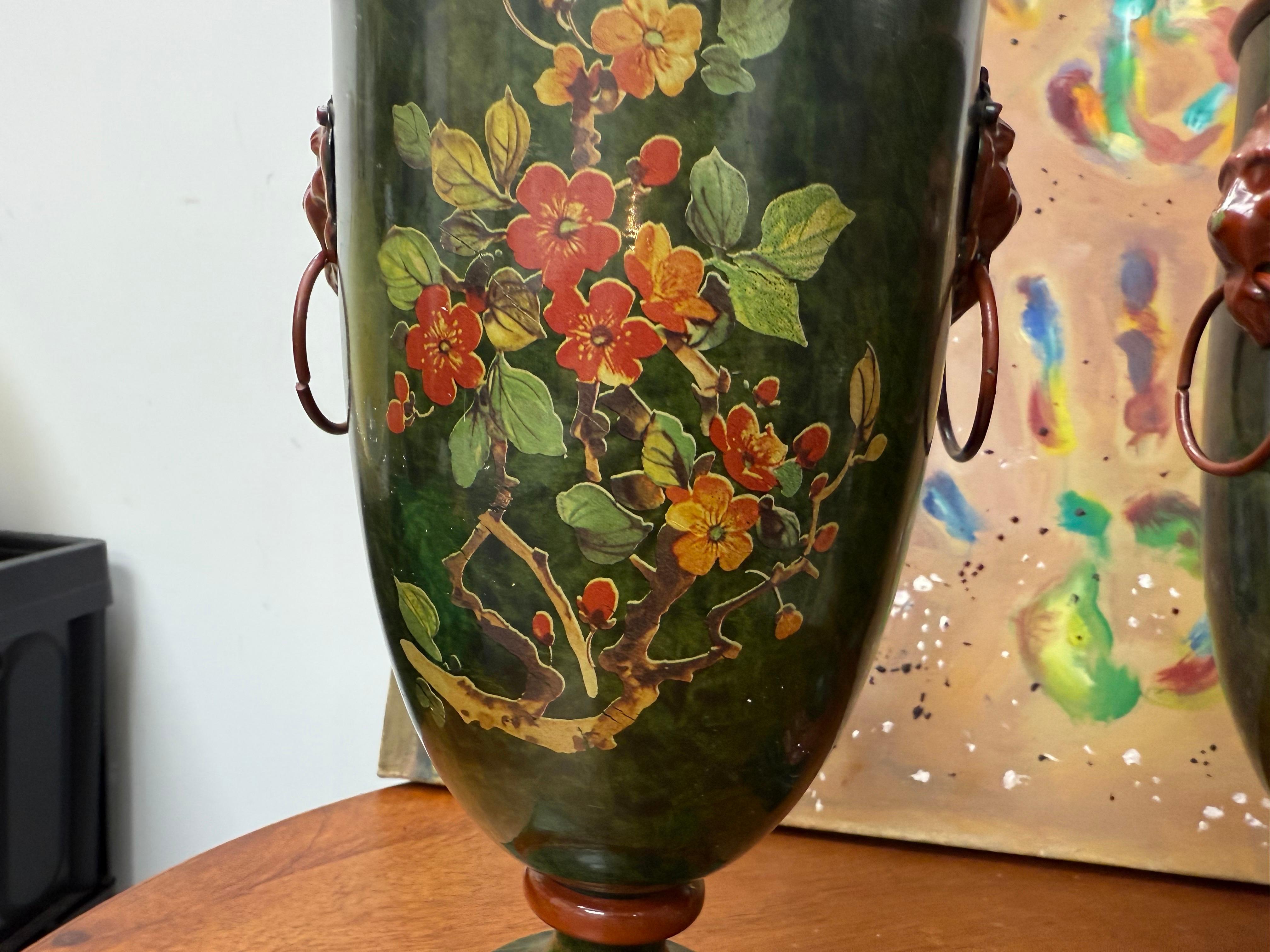 the green backgrounds decorated in with scrolling foliage and insects, with peaked lid and lions mask and loop handles, raised on a square foot 
Matched Pair of 20th c. hand-painted lidded tole Regency style chestnut urns with oval painted foliage 