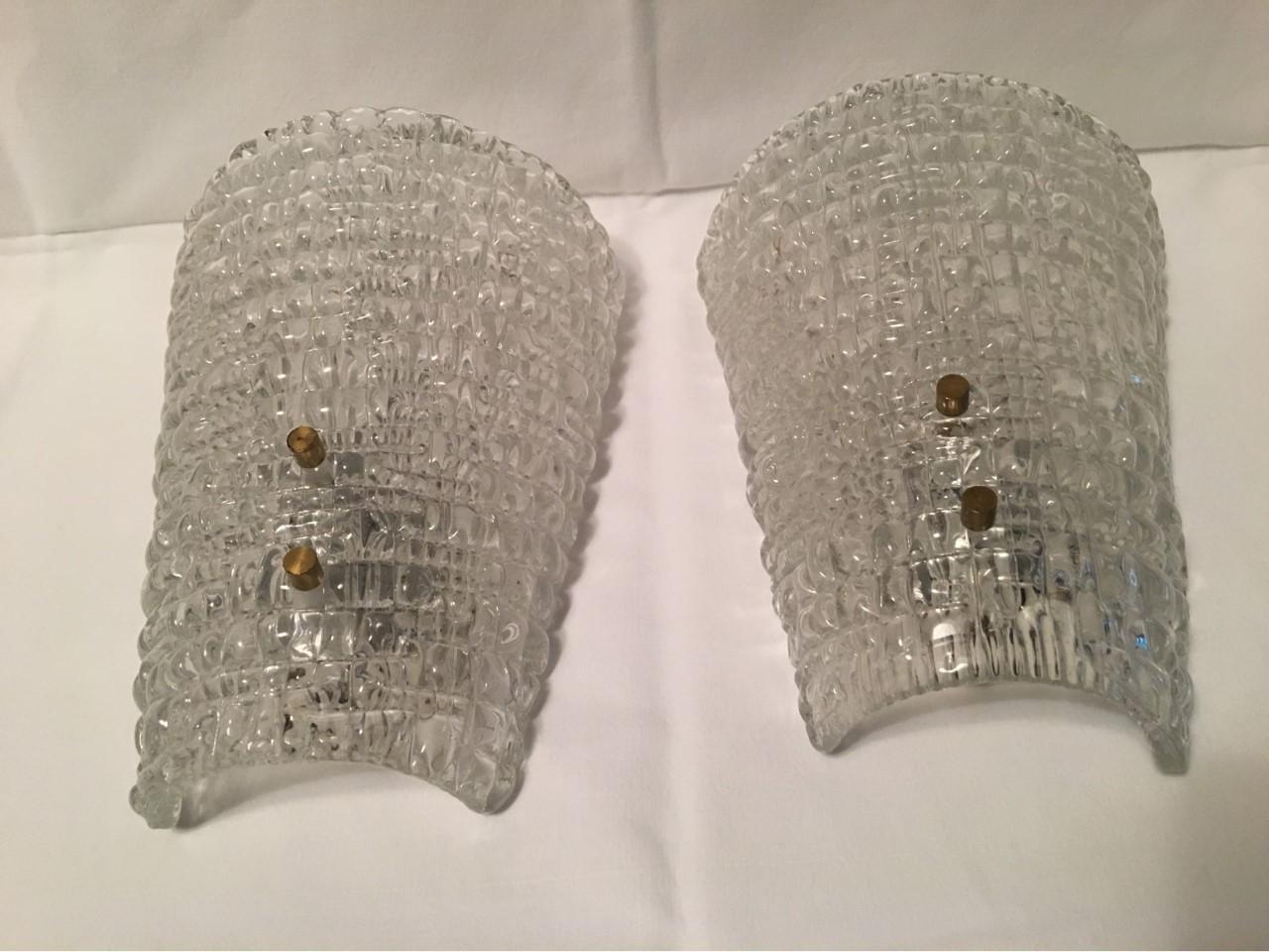 A lovely pair of Italian structured ice glass sconces. With brass screws and holders. From the midcentury, 1960s. The unique structure of the glass creates a beautiful lighting effect. Each fixture requires one European E 14 Candelabra bulb, each