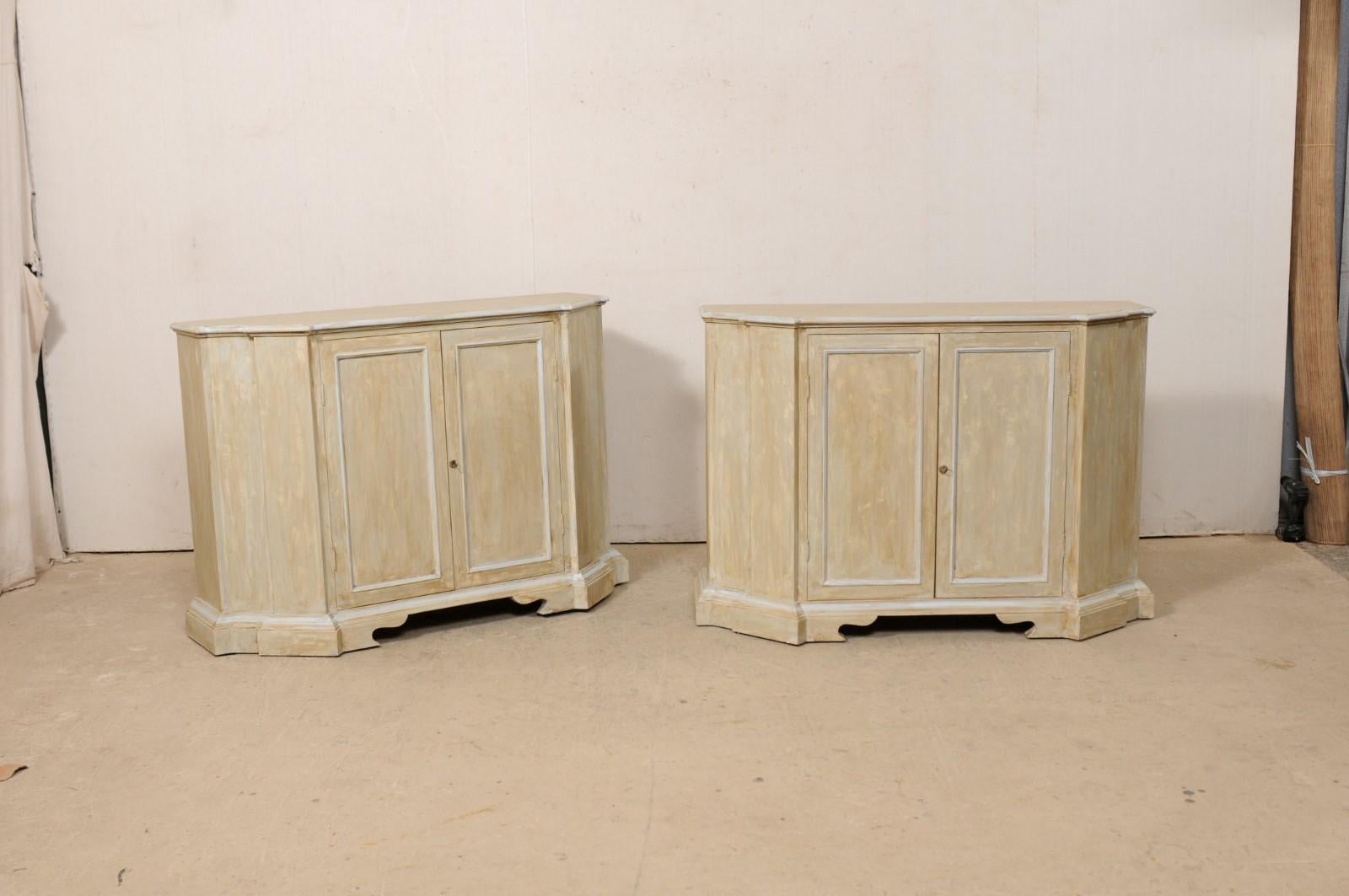 A vintage pair of Italian inspired buffet cabinets by American furniture maker Minton-Spidell. This pair of Italian style buffet consoles each feature clean lines and trim with nicely canted sides. There are a pair of recessed-panel doors set at