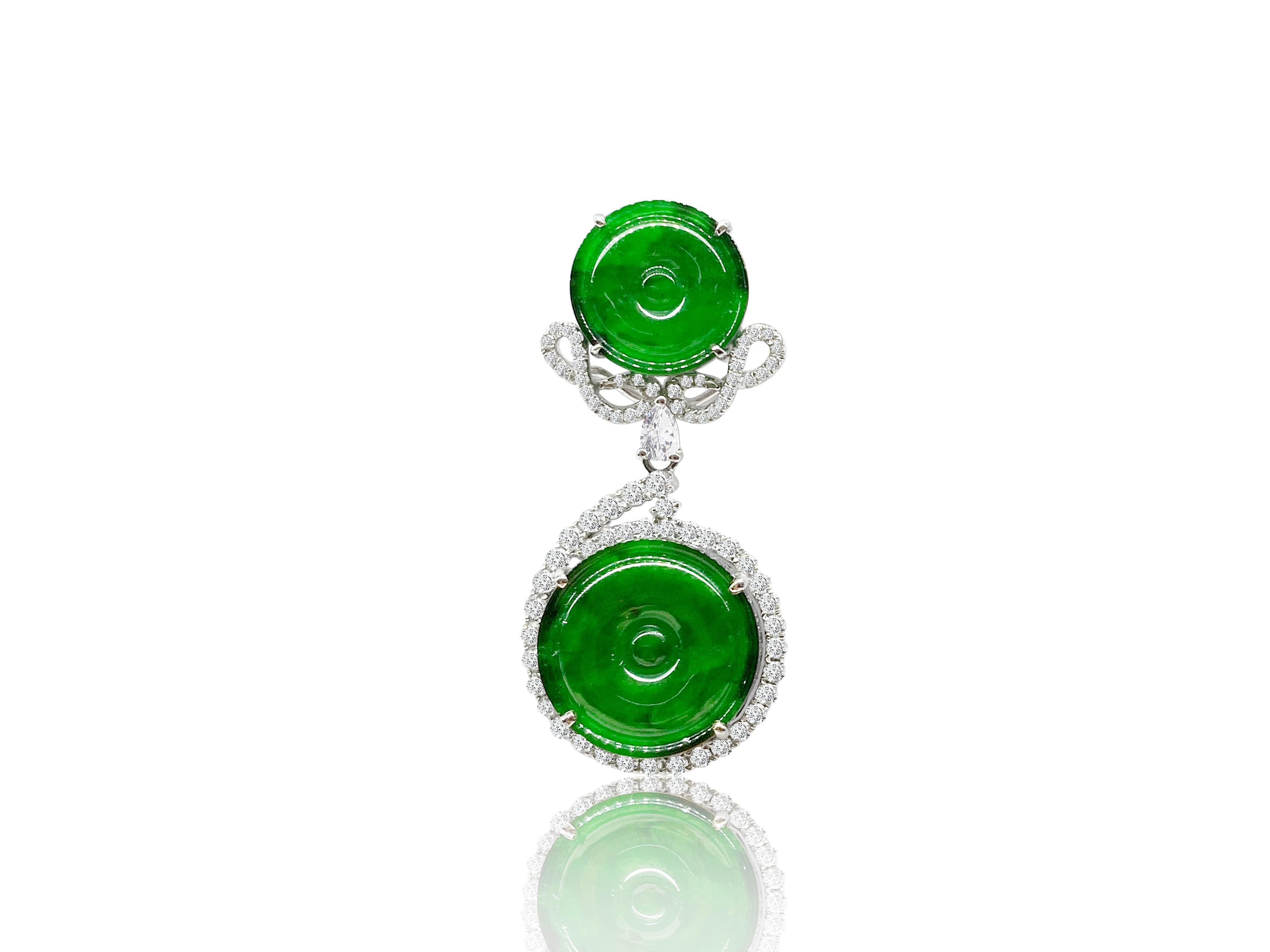 A pair of natural jadeite and diamond earrings, set with pieces of jadeite of vivid emerald green colour with very good translucency, surrounded by brilliant-cut diamonds weighing 1.52 carats, mounted in 18 karat white gold. The lower part of the