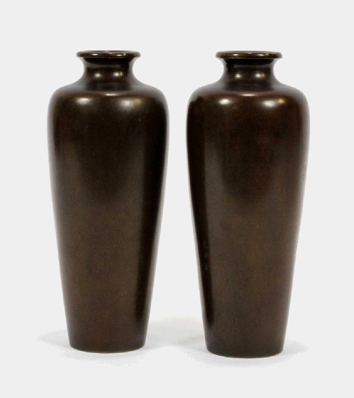 A pair of elegant vases of solid oiled bronze from the Meiji era, Japan (1868-1912). In a Classic Meiping shape, the pair has a mirrored inlay with gold, silver and red enamel that depicts a pair of roosters perched on plum branches in blossom. The