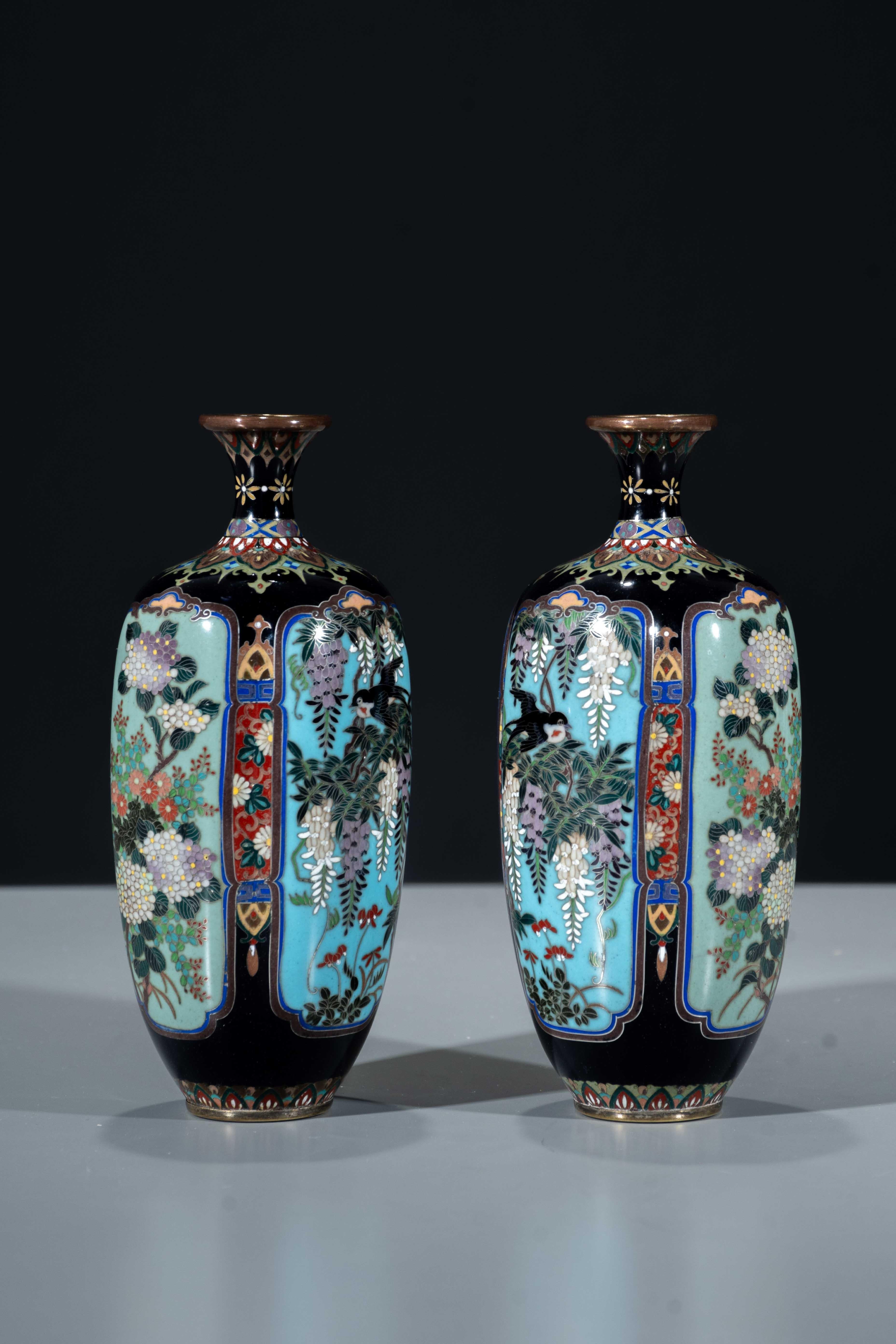 A pair of lobed cloisonné vases with dark blue ground, decorated with naturalistic subjects within four reserves. 

The reserves display different seasonal floral motifs: wisteria with birds in flight, chrysanthemums, irises, and magnolia, rendered