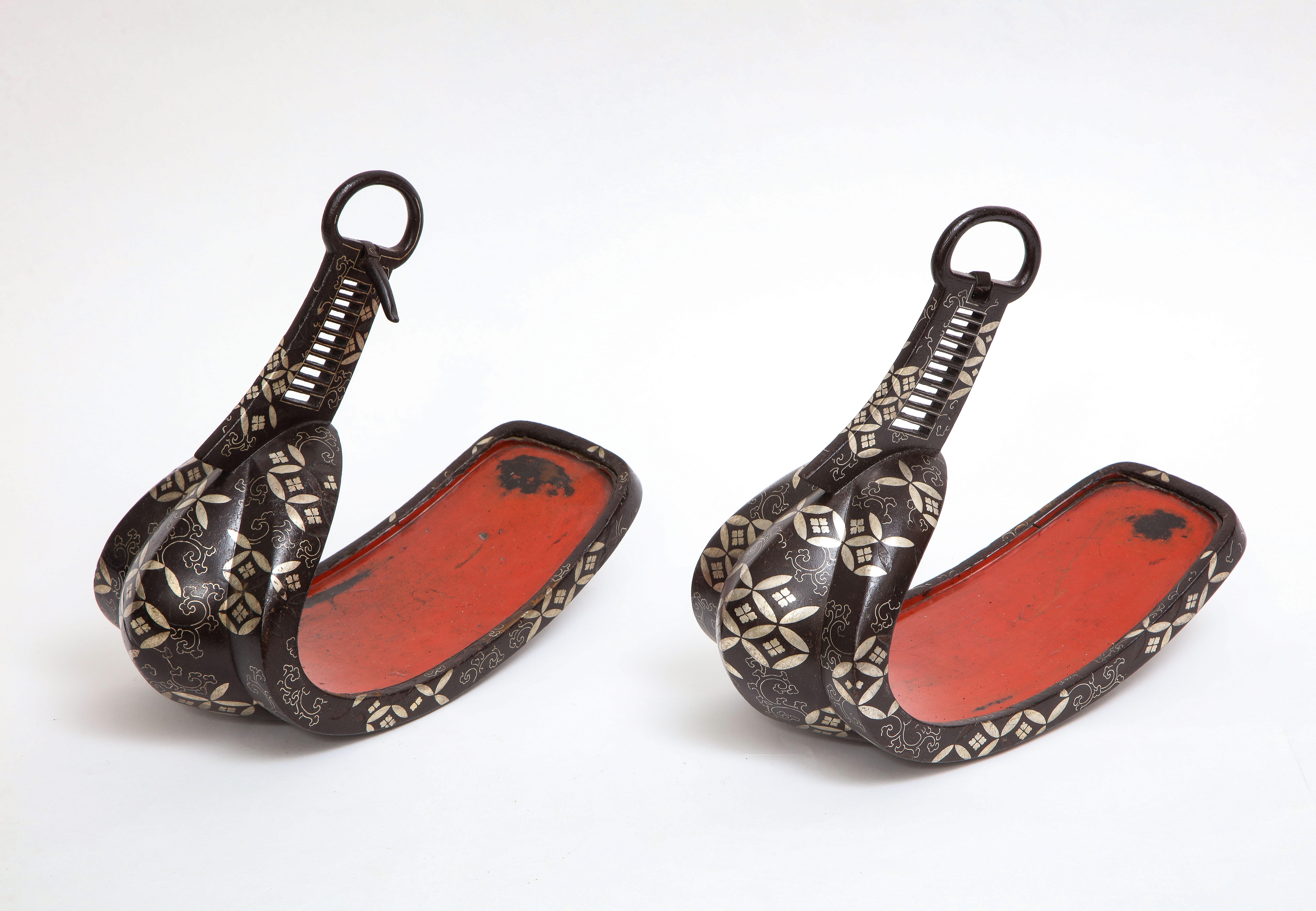 A Pair of Japanese Edo Period (1603–1867) iron, silver inlaid, and red lacquered stirrups (Abumi). Each of typical form, made of iron with silver inlay on the front with floral blossoms borne on leafy vines, with silver inlaid clouds underneath. The