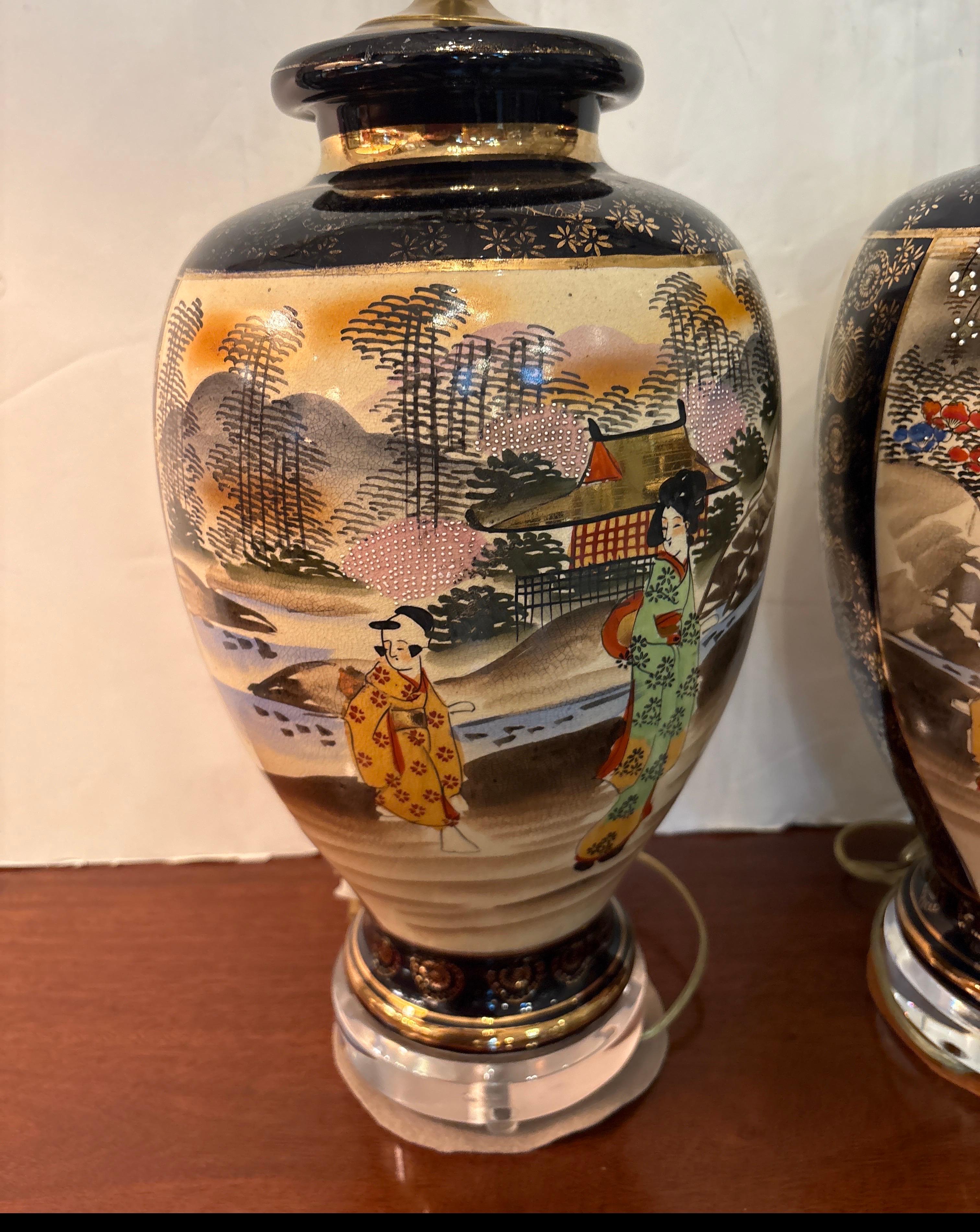 Une belle paire de lampes japonaises Satsuma du milieu du 20ème siècle.  Le recto et le verso présentent des scènes assorties en miroir sur un fond bleu cobalt reposant sur des bases rondes en acrylique.  La hauteur totale est de 30 pouces et les