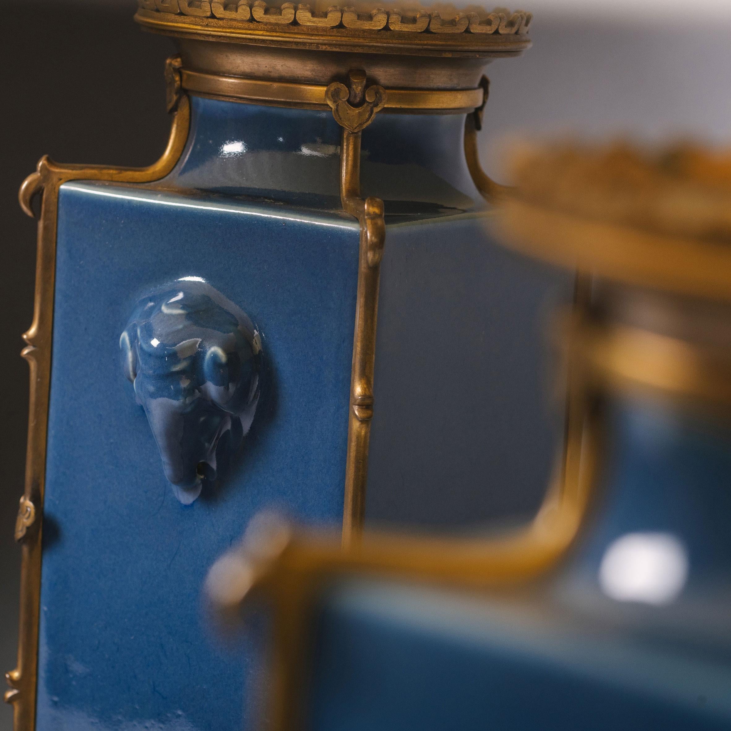 A Pair Of 'Japonsime' Gilt-Bronze-Mounted Powder-Blue Porcelain Vases, Mounted As Lamps. By Ferdinand Barbedienne, Paris.

Each with a square shaped body. The sides decorated with elephant head handles. The bases corned by elephant heads, each