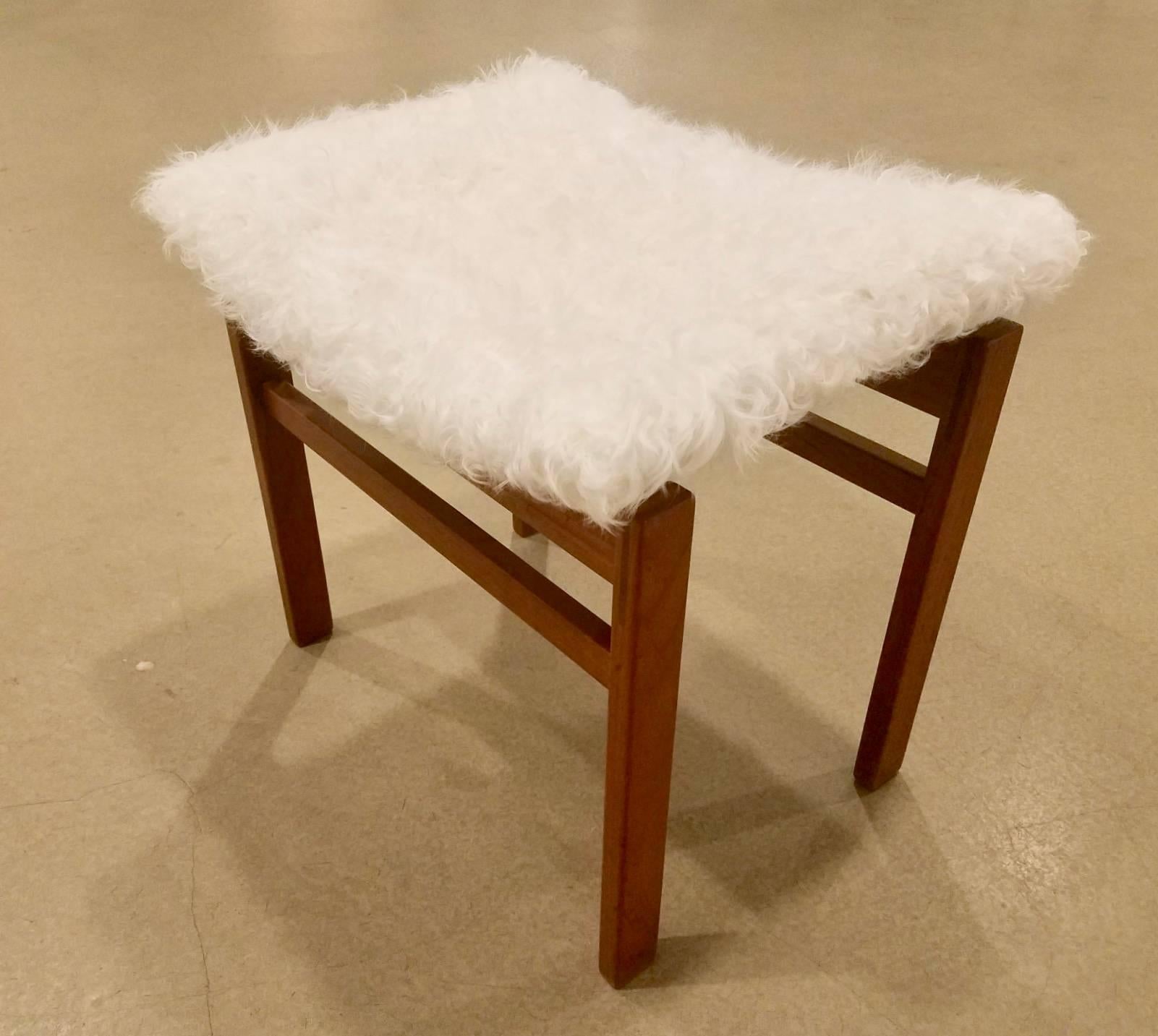 A pair of Finn Juhl stools for John Stuart, the concave seats resting on
ruddy colored wood newly upholstered in white alpaca with manufacturer's label on the underside.