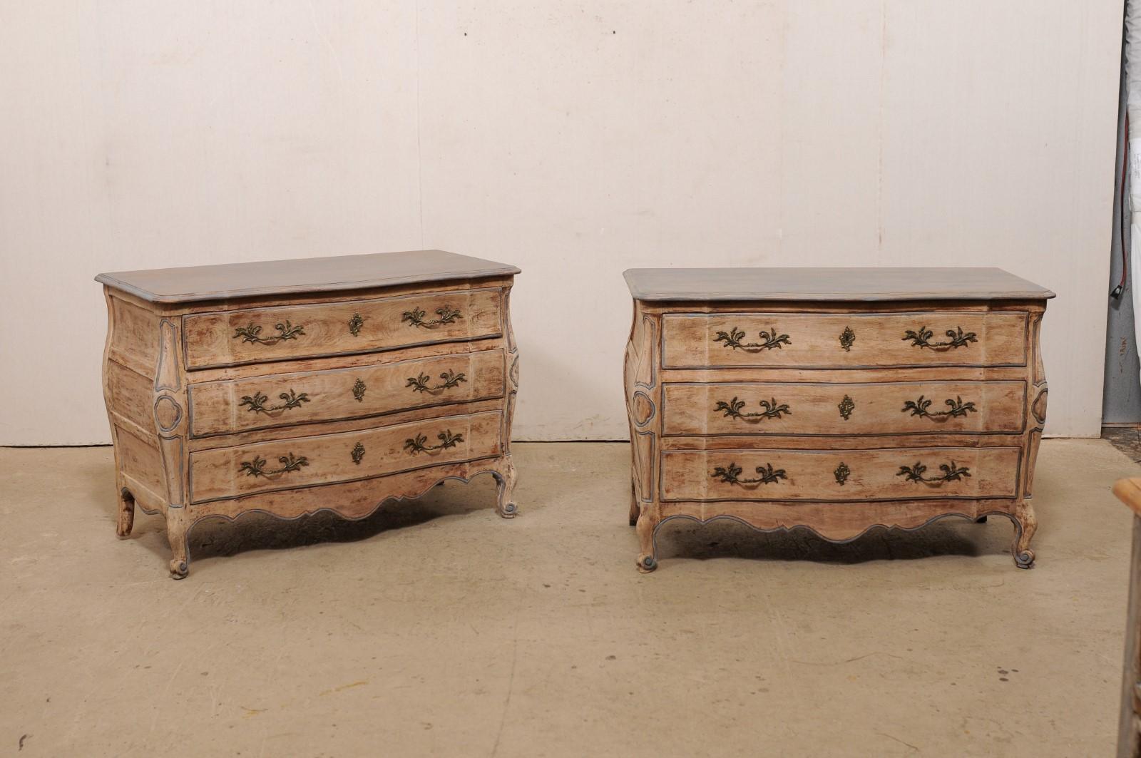 A pair of French-style serpentine chests from American furniture maker John Widdicomb, circa 1960's. This pair of commodes have been designed with French influences, and each feature slightly overhanging tops, with rounded corners, and whose shape
