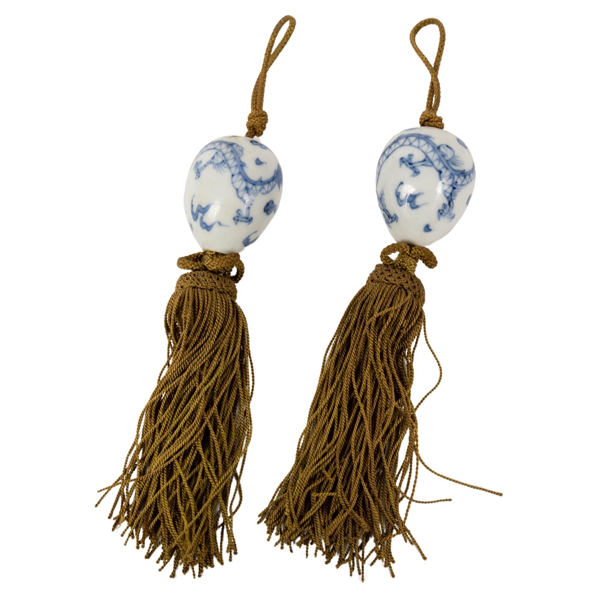 A pair of kakemono weight in porcelain decorated with dragons in a cloudy sky