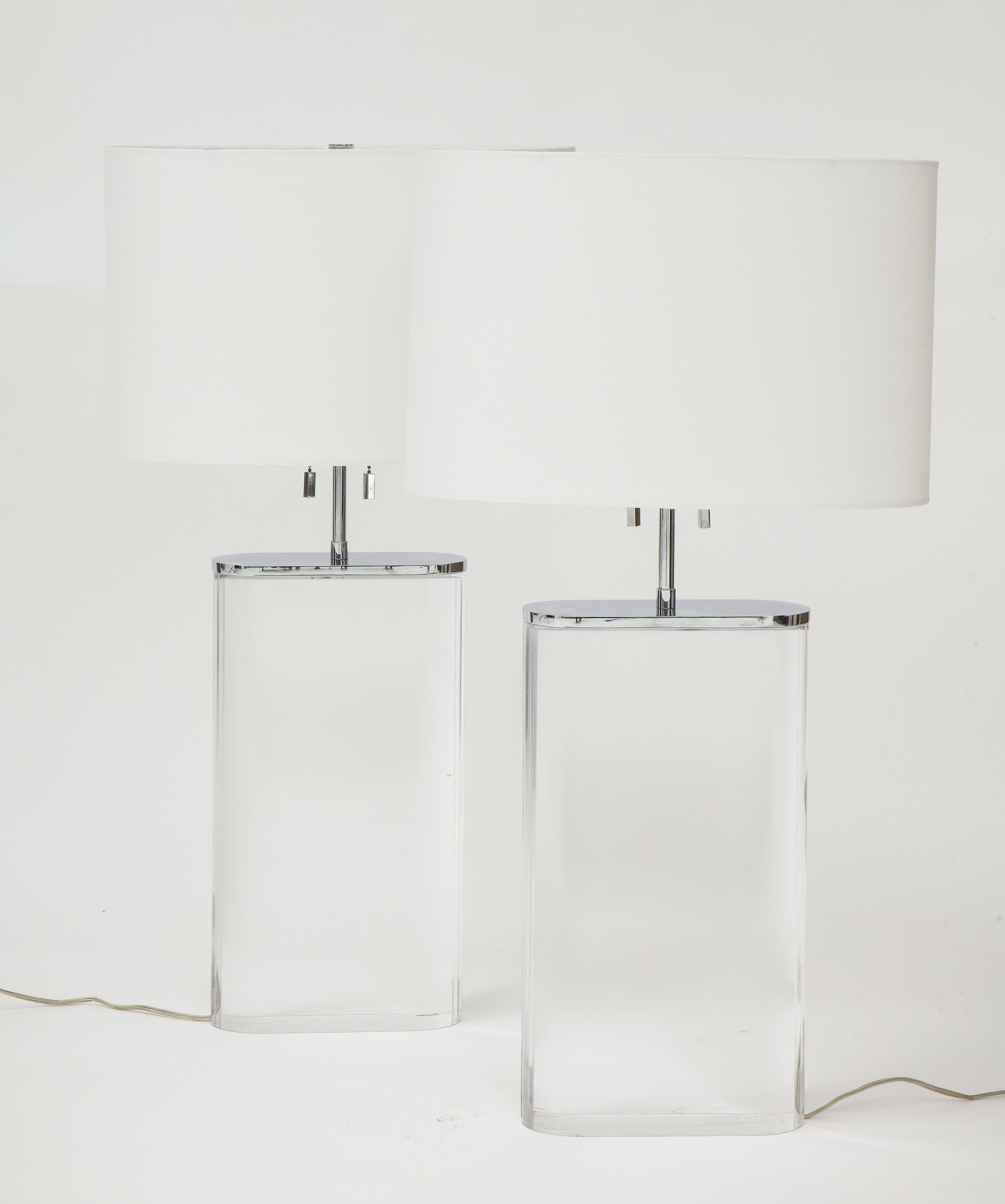 A large scale pair of Lucite and chrome mounted oblong form table lamps by Karl Springer. Purchased from Karl Springer circa 1982-1984, with new shades. Adjustable height.
Lucite base: 16.3/8 H x 9” W x 3 ½” D
To top of shade 29in.