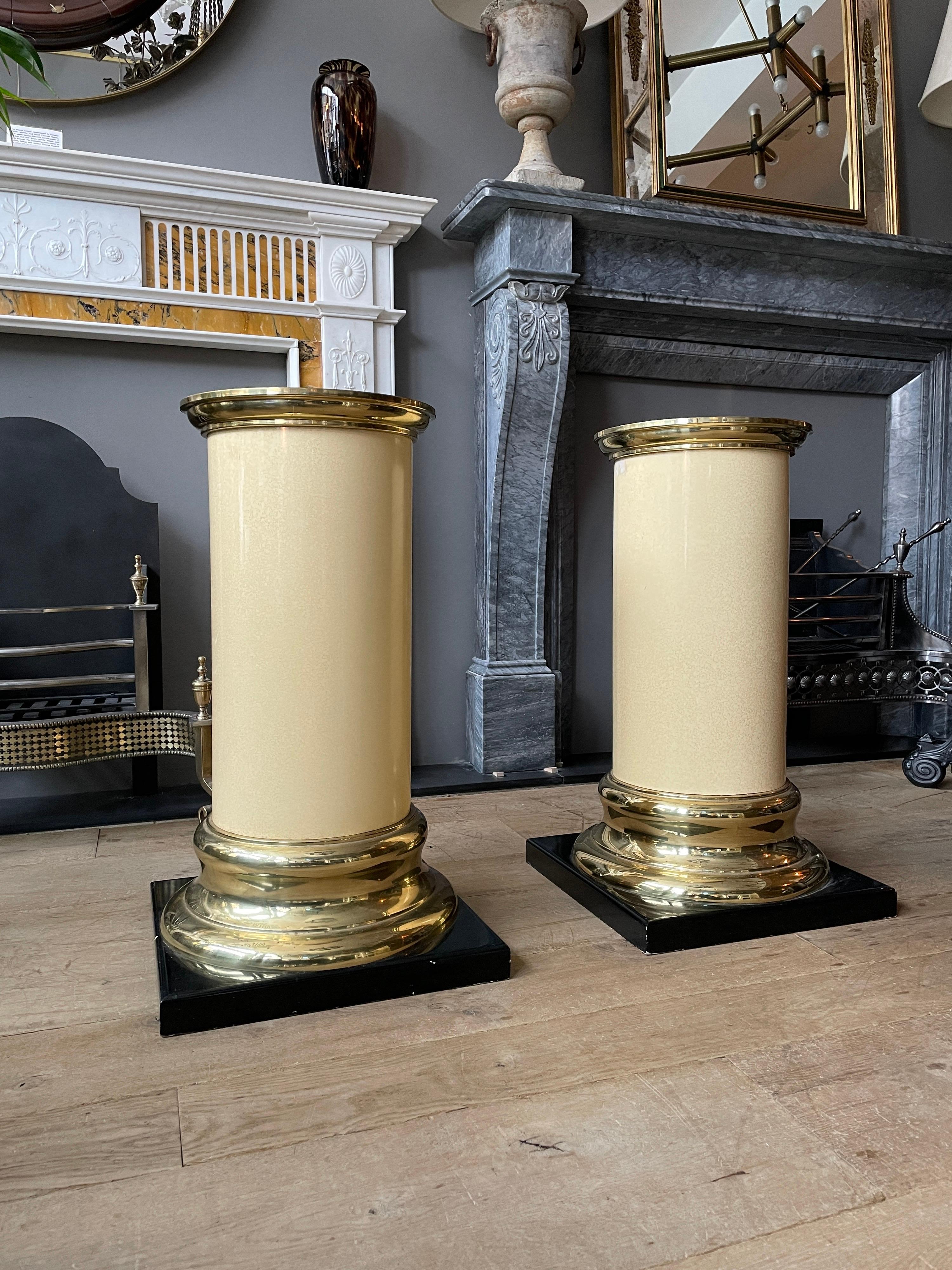 A late 20th century pair of pedestals with ebonized bases brass soccles and capitals with cream lacquered plinths. American circa 1970 by Mastercraft.
