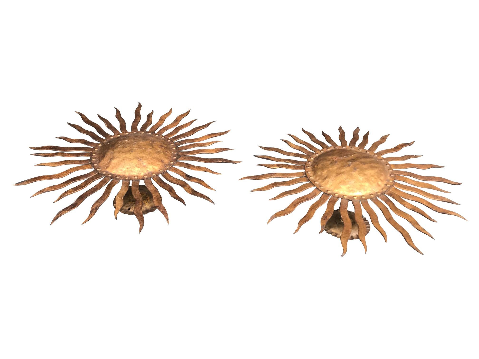A pair of large 1950s wrought iron sunburst wall sconces with gilt finish. Each sconce is mounted from a scolloped base plate with central rod, so they can be mounted on the wall or ceiling. Each has 2 light fittings behind and re-wired and PAT