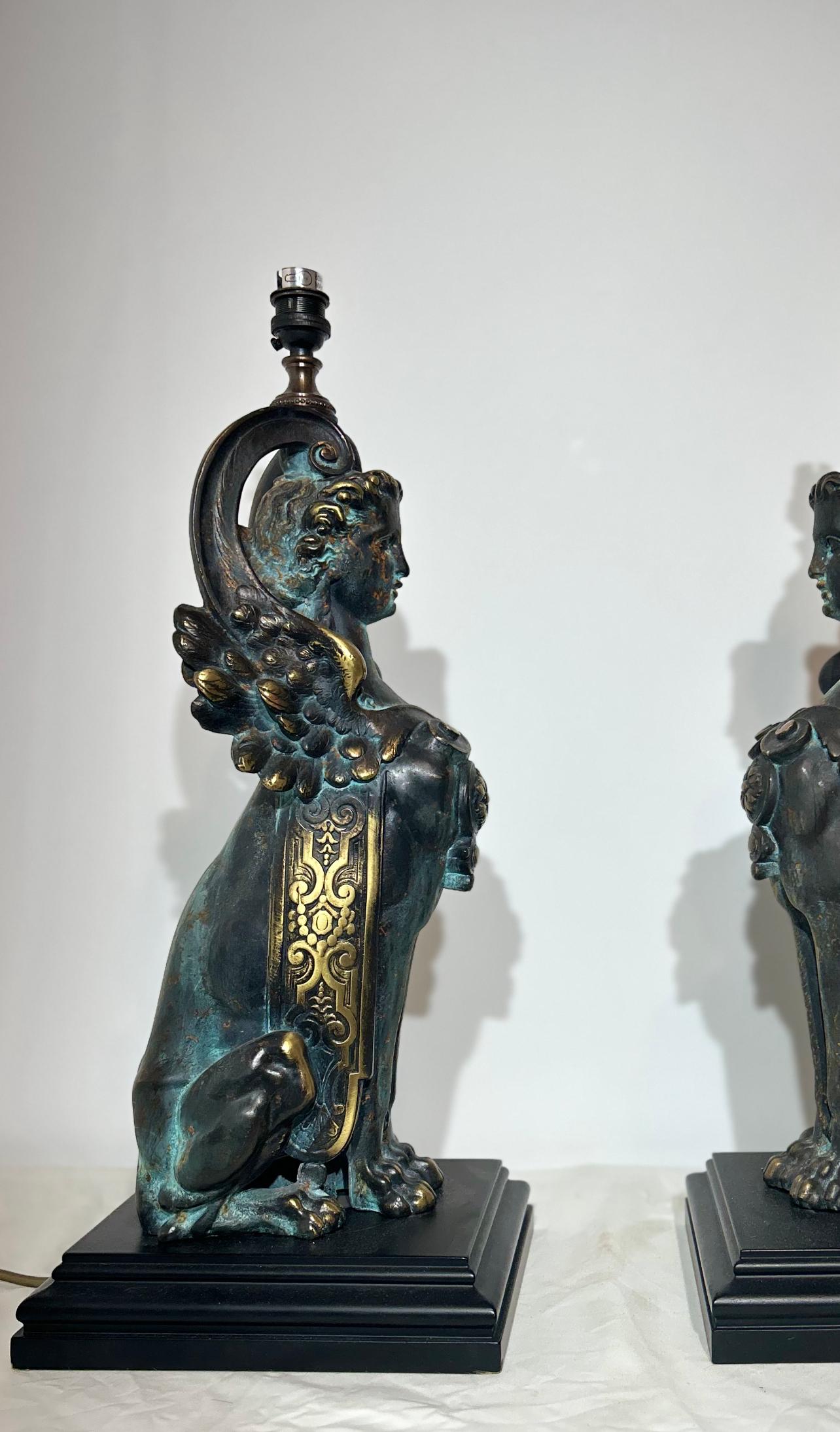 A pair of Mid-20th Century French Empire gilt patino bronze sculptured sphinx lamps with original pleated silk lamp.