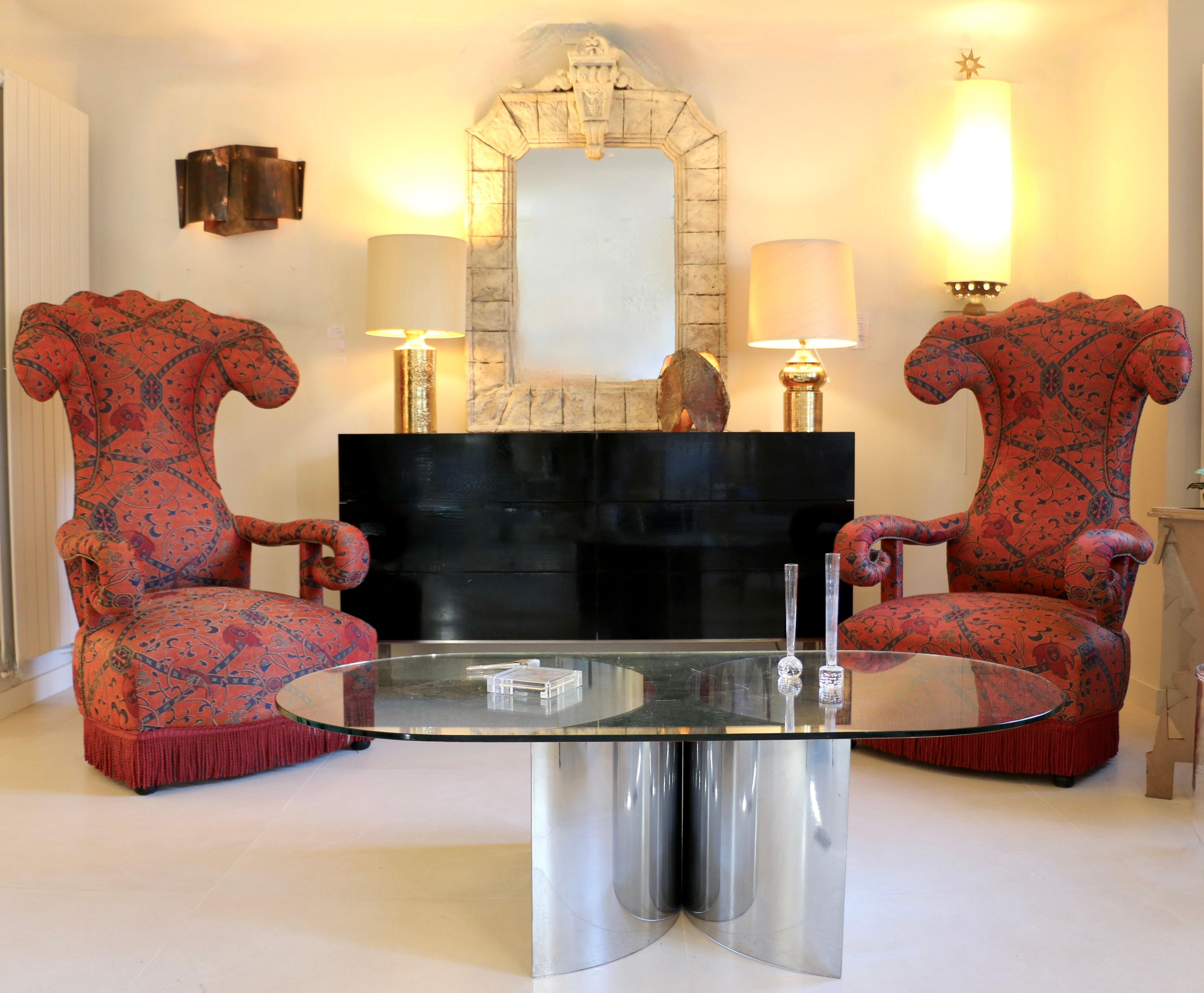 Una coppia di grandi poltrone in seta rossa con alti schienali curvi e braccioli arrotolati. Francia, inizio del XX secolo.