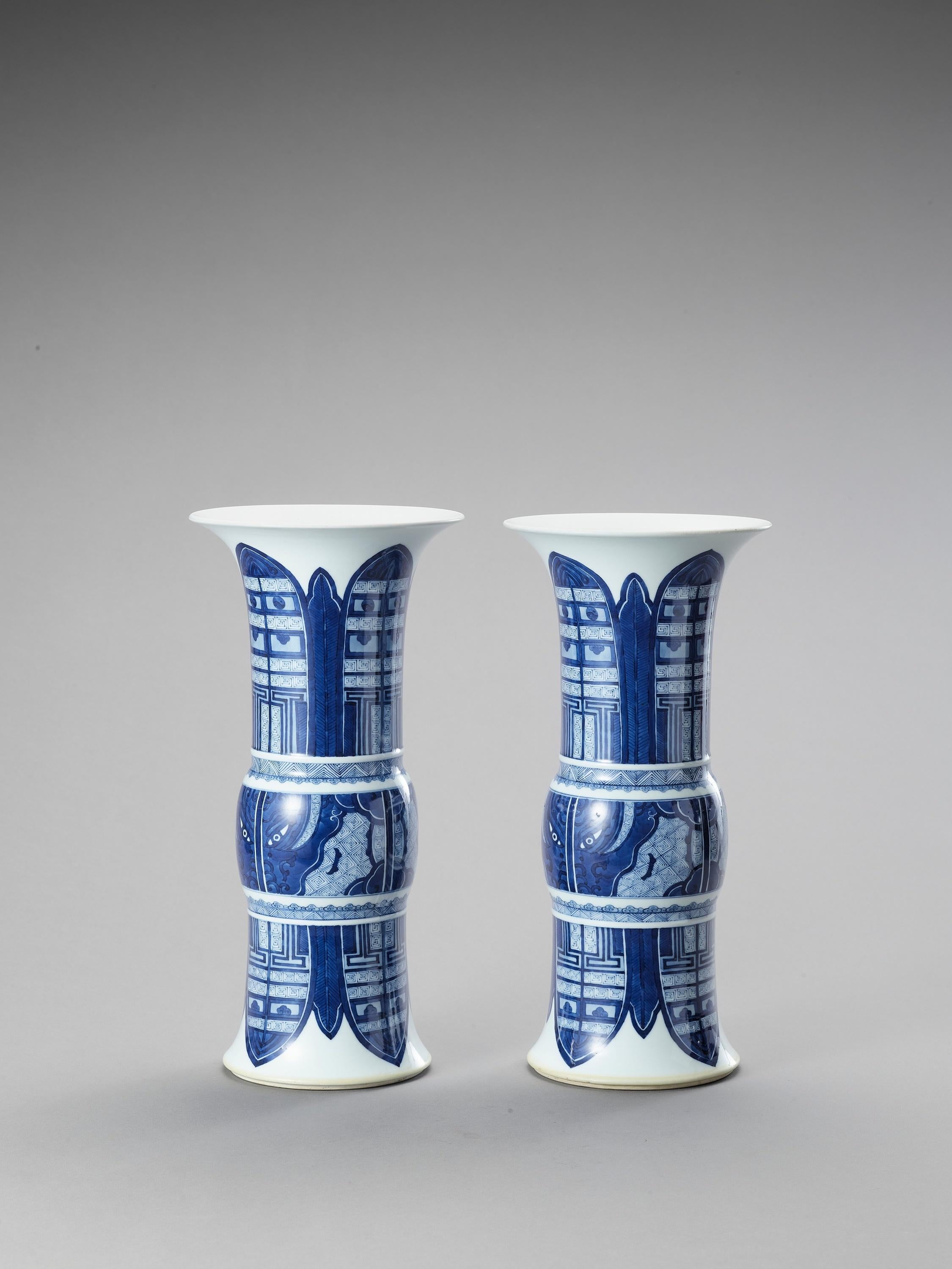 A pair of large beaker vases, China, 19th Century

The tall cylindrical bodies rising from tapered feet to trumpet mouths, with rounded central sections, each between two thin moulded fillets and painted in underglaze blue. The central section