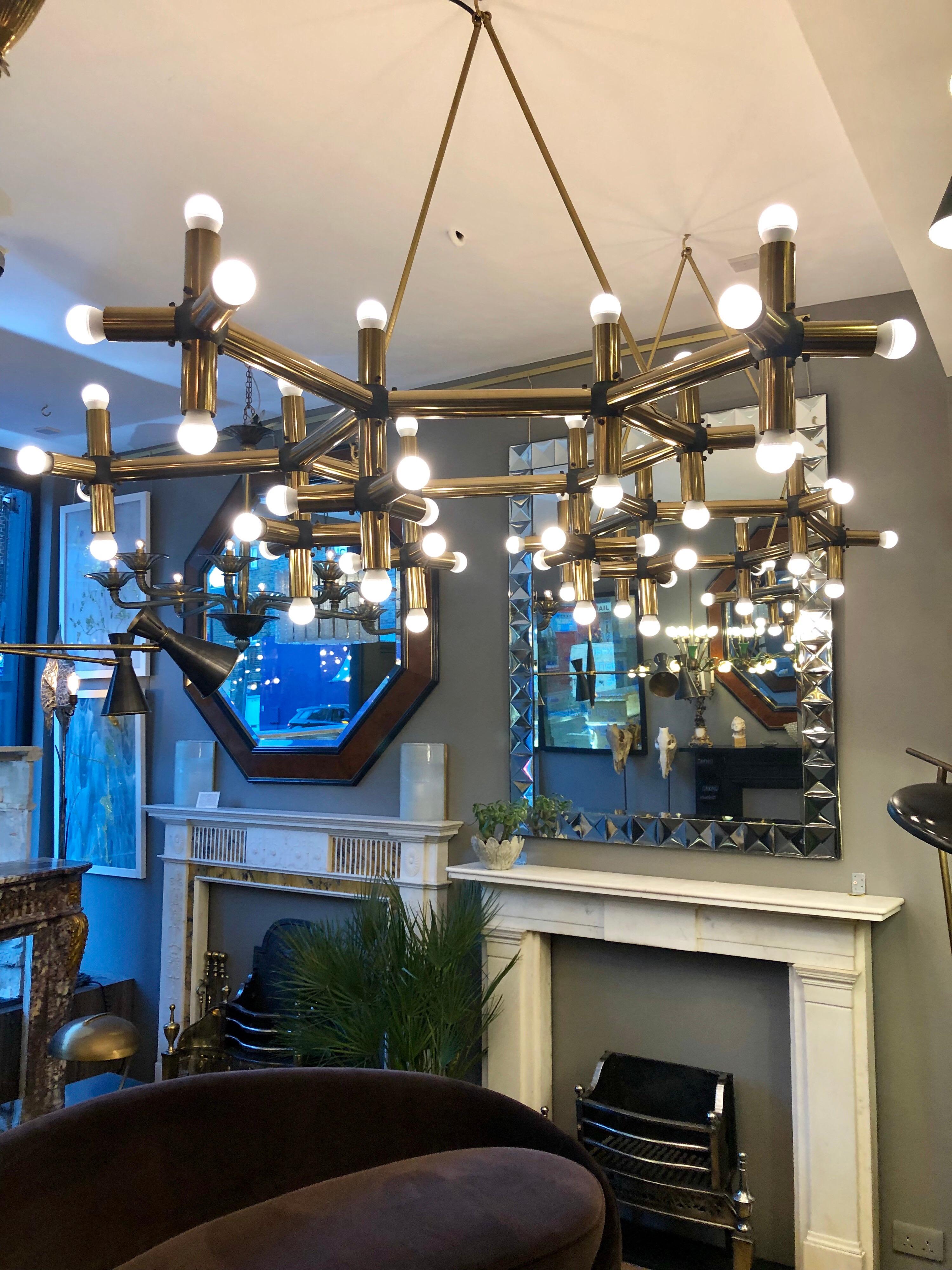 An unusual and very large pair of tubular geometrical “ lichtstruktur “ chandeliers in brass by Robert Haussmann. Having 54-light fittings in each light. Hung from the ceiling with brass matching hooked rods. Imported from Paris and installed in
