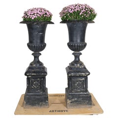 A pair of large cast iron urns on iron stands, early 20th c