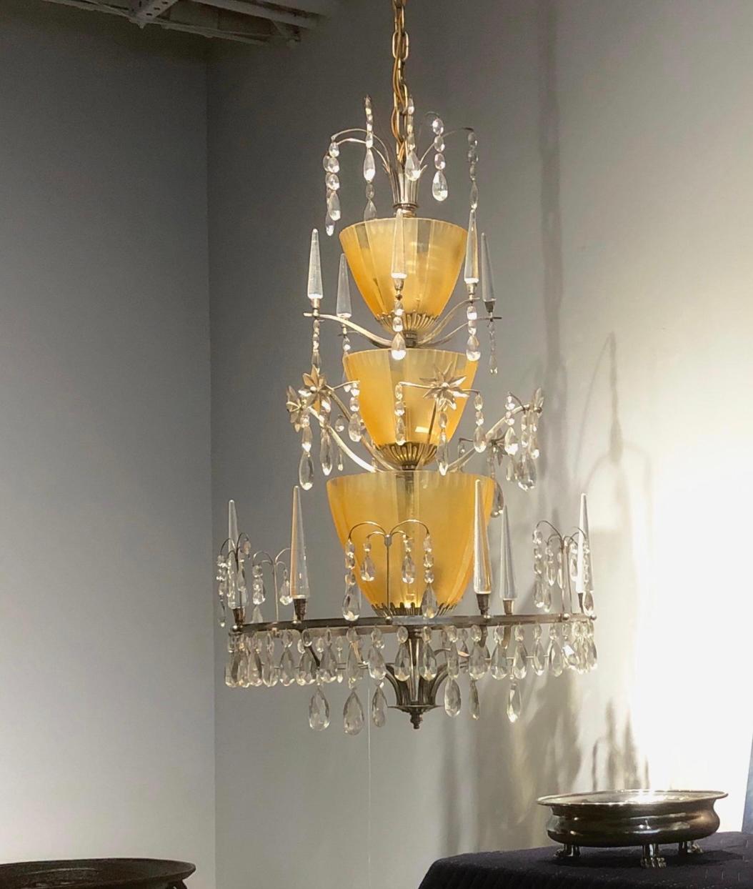 A pair of large and rare Swedish Grace Chandeliers, design attributed to Elis Bergh, Sweden, Circa 1920th. Silver plated brass frame with 3 amber glass shades and crystals decoration.  9 lights. Existing wires , rewiring available upon request.