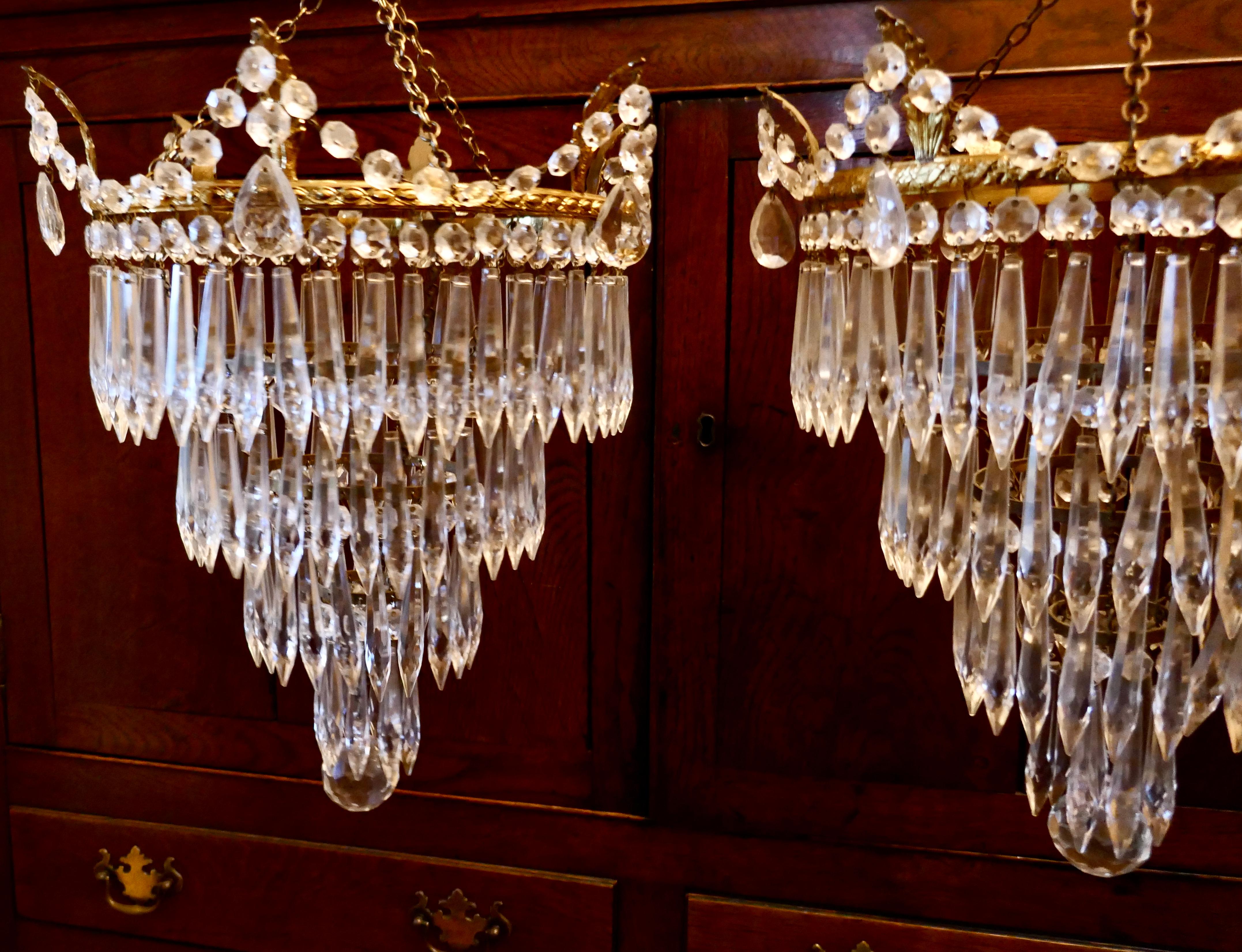 A pair of large crystal waterfall chandeliers

These are good quality pieces, waterfall tiered pendant chandeliers, these delicate lights have four layers of crystal icicle pendants hanging from a circular brass frame with a large faceted crystal