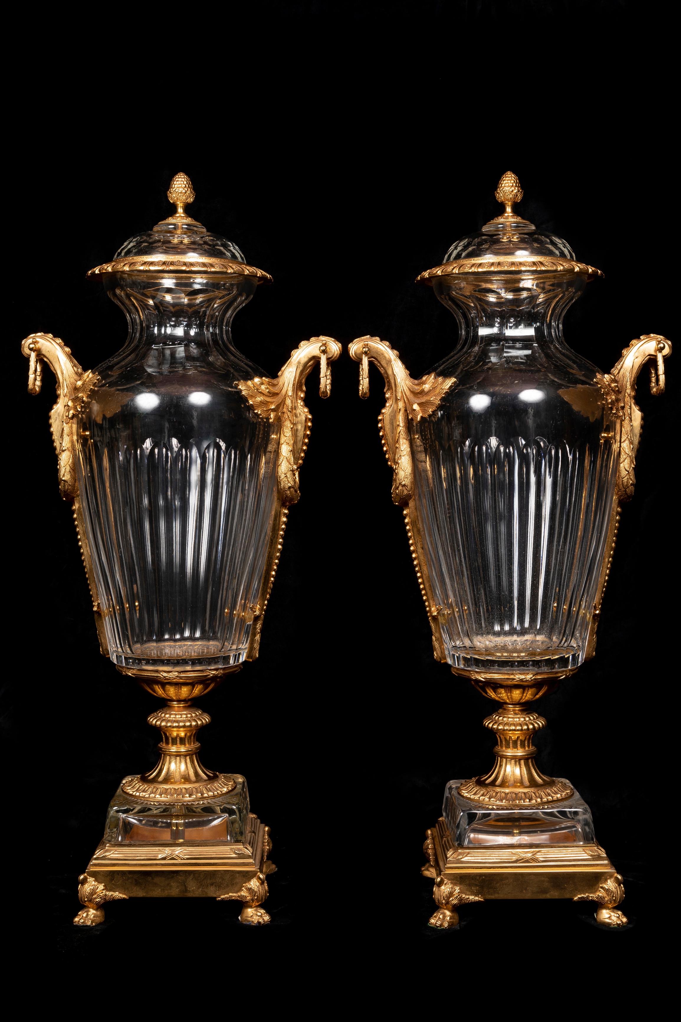Ein Paar sehr großer französischer Urnen im Baccarat-Stil aus vergoldeter Bronze und geschliffenem Kristall, die von hervorragender Handwerkskunst bedeckt sind. Jede Urne ist mit feinen Doppelgriffen aus vergoldeter Bronze verziert und ruht auf