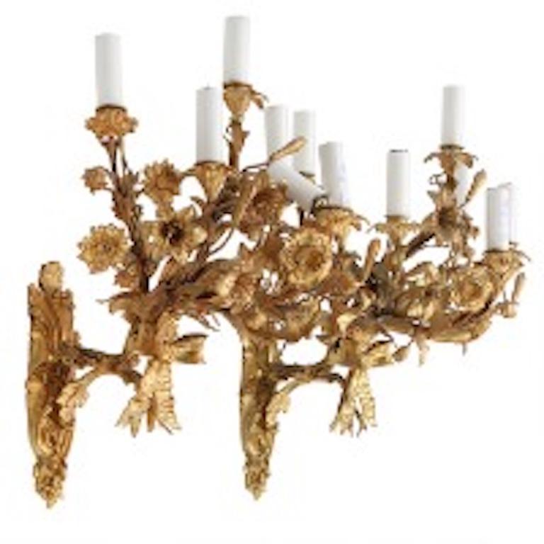 This exquisite pair of bracket lights are approximately two feet in height. They are comprised of a motif of ribbons and foliage and florals and are beautifully rendered in the fashion of the great French metal workers of the period   Each bracket