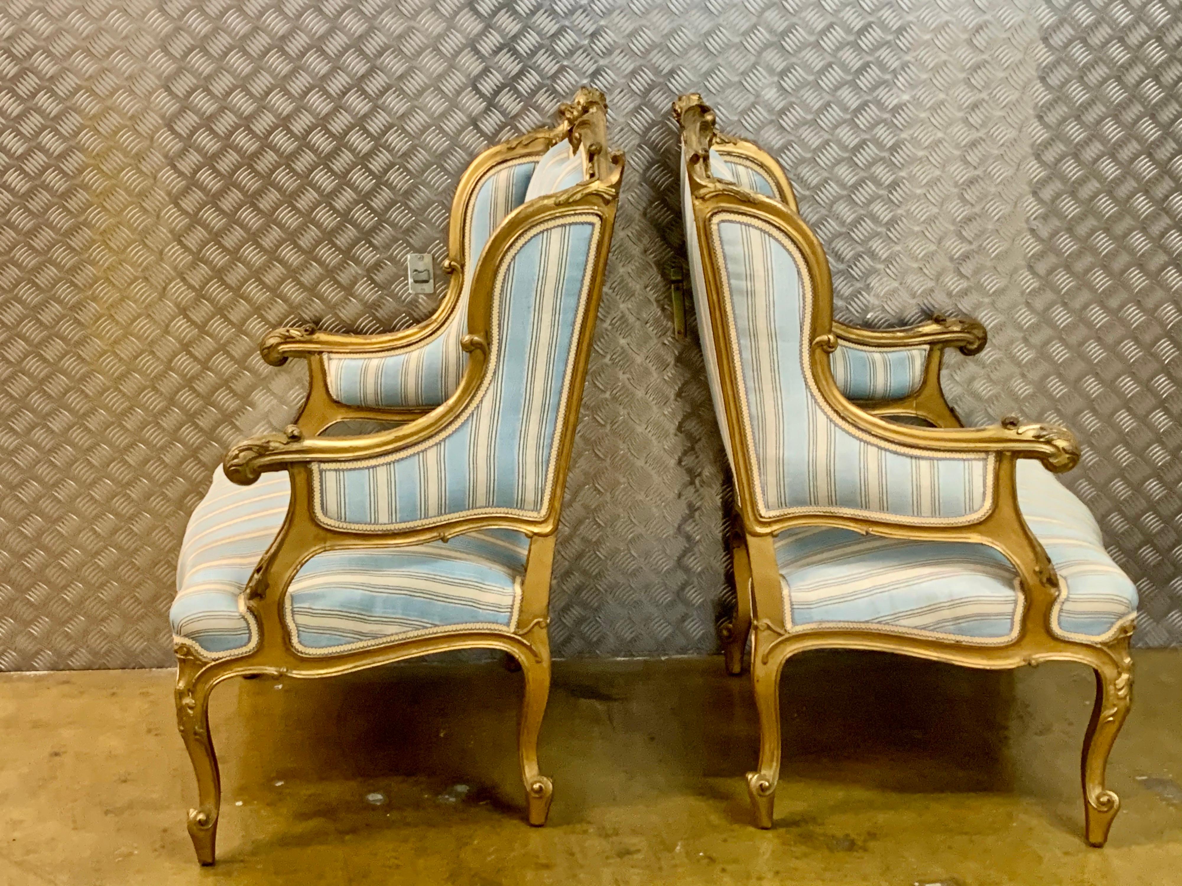 A pair of very nice French upholstered wing back chairs, the gilt frame with scroll carved cresting and acanthus arms, serpentine frieze on cabriole legs, loose seat cushion, Measures: W 76 cm, D 68 cm, H 123cm. 
The condition is very good and they