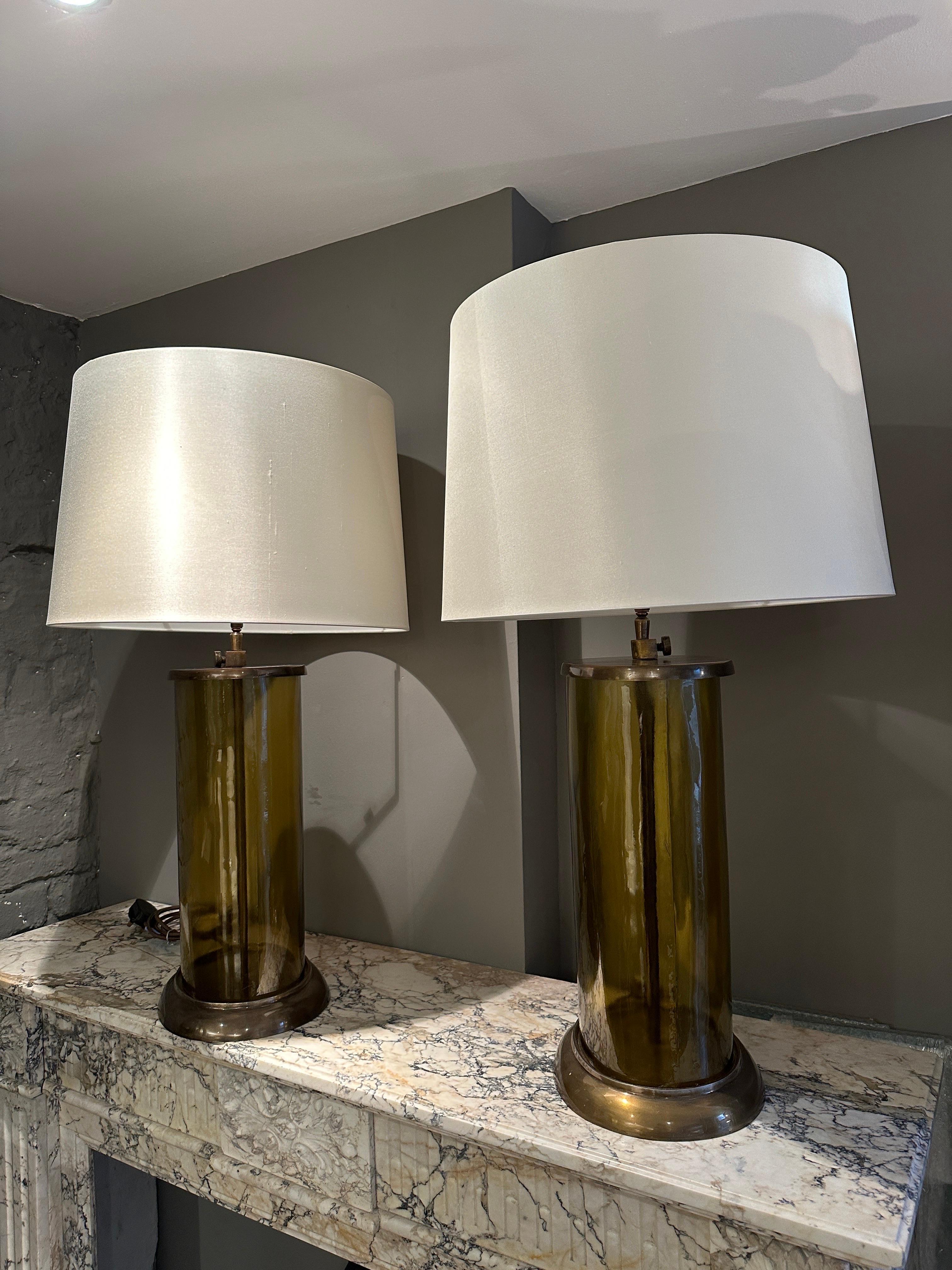 A pair of large scale table lamps in Bronze patinated brass and bottle green glass. Newly re wired with silk flex and inline switch. Off white new silk shades included. Imported from the Netherlands, apparently bespoke made for a certain position in