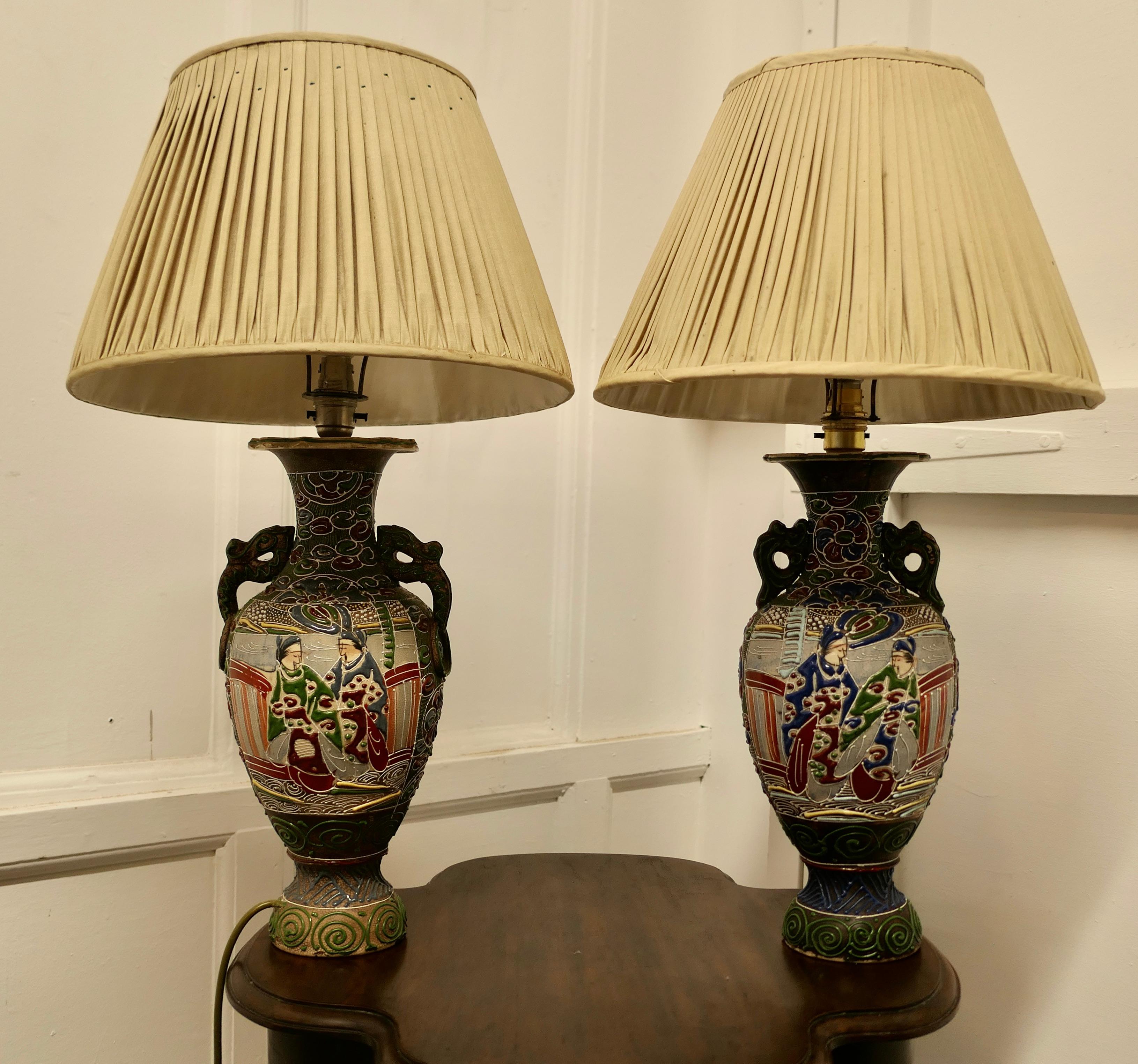 A Pair of Large Japanese Satsuma Lamps

A pair of large Japanese Moriage Satsuma Handpainted Lamps dating from the Early 20th 
The lamps are not exactly identical they have scenes which mirror each other
The Lamps are all working, there is a