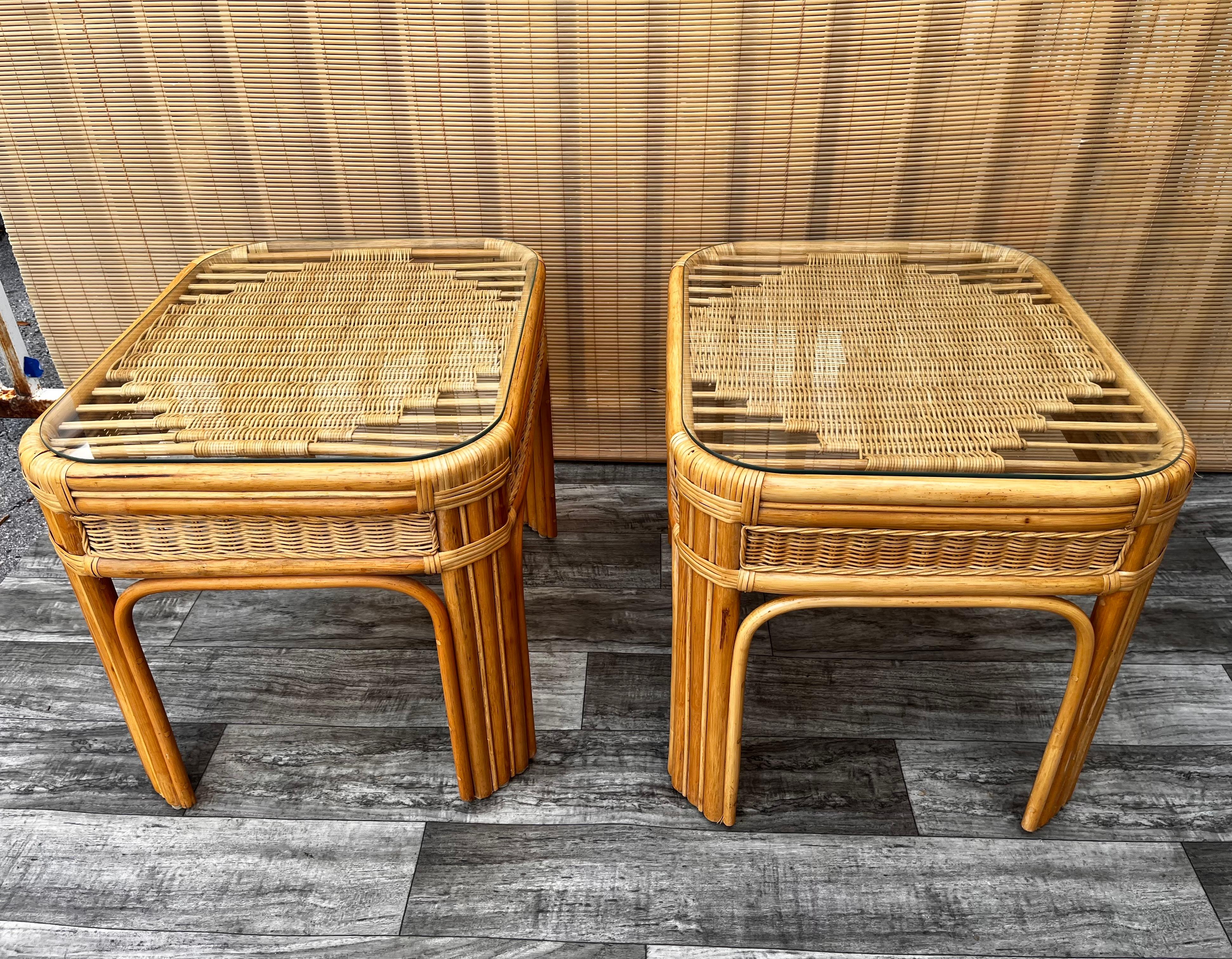 A pair of large late 20th century coastal style weaved rattan side tables. circa late 1980s
Features a beautiful hand woven top detail, rounded corners, finished in a natural rattan color, and a removable glass top.
In excellent original condition