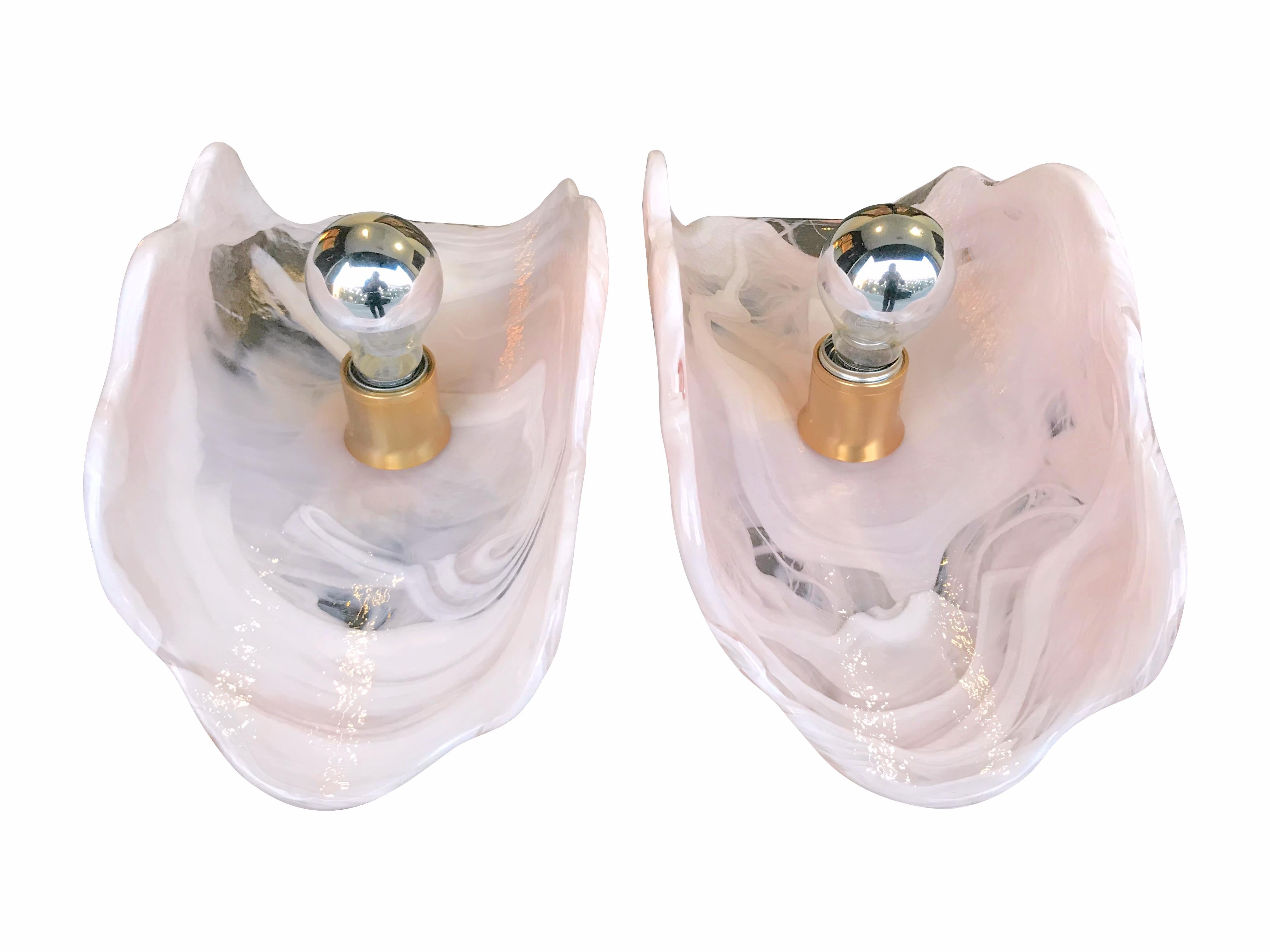 A pair of large Mazzega pink and white Lattimo glass wall sconces with brass wall mounts. Re wired with new fittings and PAT tested.

 The black in the glass on the photos is the surface beneath, as those are the clear parts in the glass.