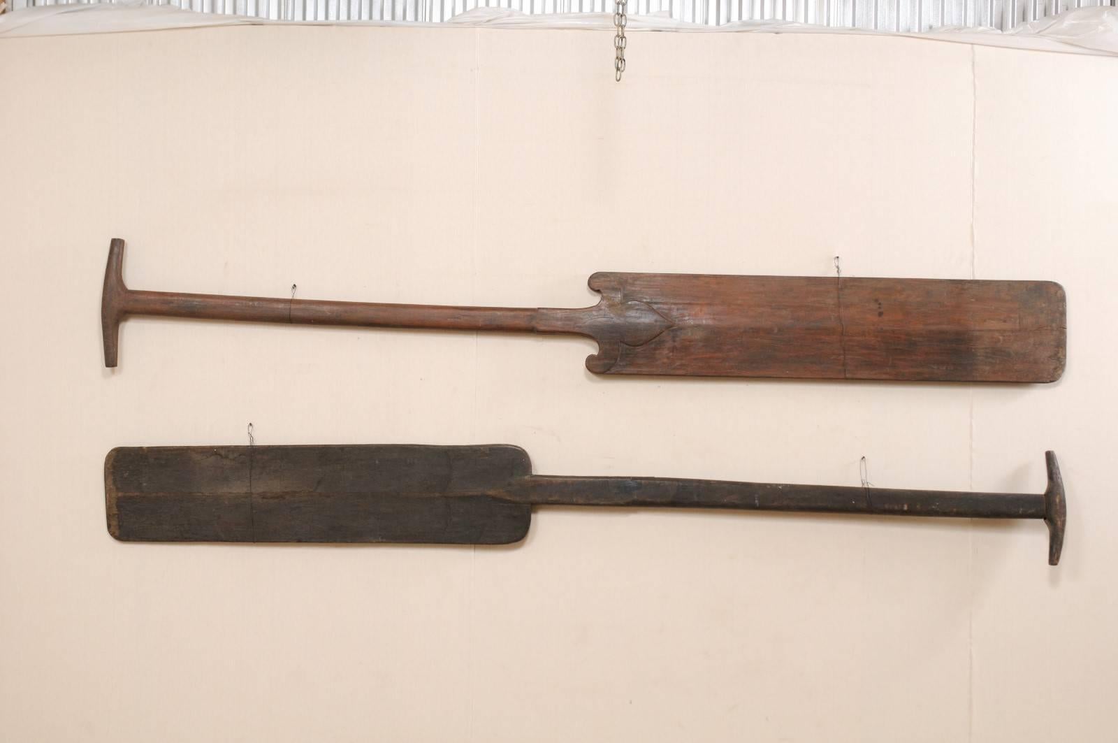 A pair of large-sized South Indian (Kerala) wooden boat steering paddles from the mid-20th century. This pair of hand-carved boat oars from Kerala are an impressive 11+ feet in length. The paddles have as a beautiful salt water patina and lovely