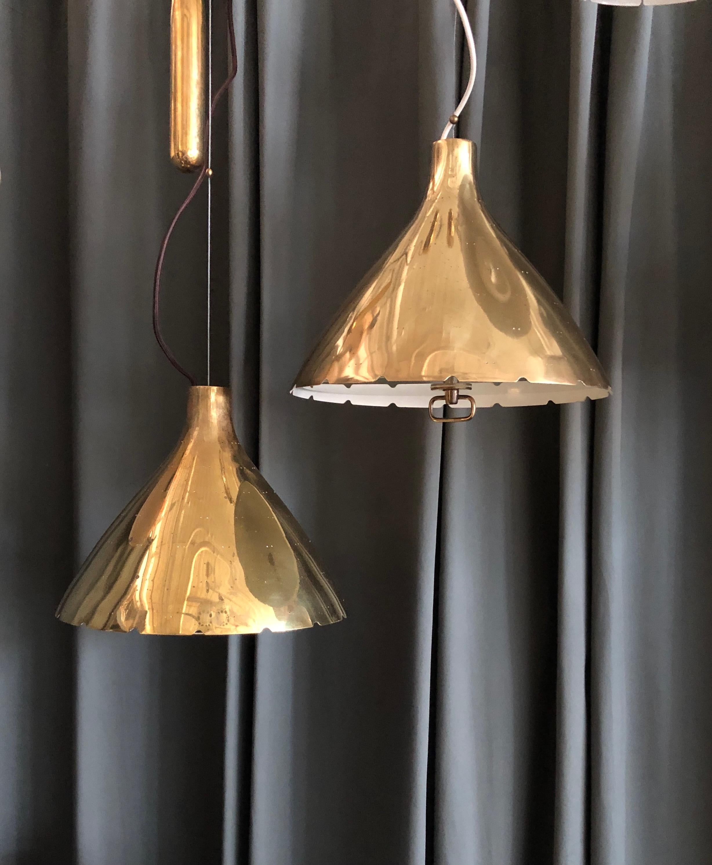 A pair of large pendants designed by Paavo Tynell for Taito Oy, Finland, circa 1950th.
Polished perforated brass shades with frosted glass defusers on counterweight.
Each fixture has 2 Edison type sockets. One fixture with brown cloth cord, the