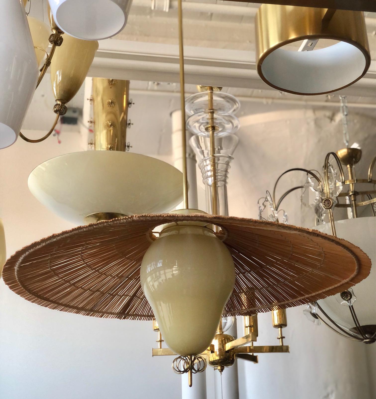 A pair of large pendants designed by Paavo Tynell for Taito Oy. Model 1090. Finland.
 Very rare version with filigree glass bawl and  straw shade. Marked by manufacturer.
Rewiring available upon request. The glass shade height 12