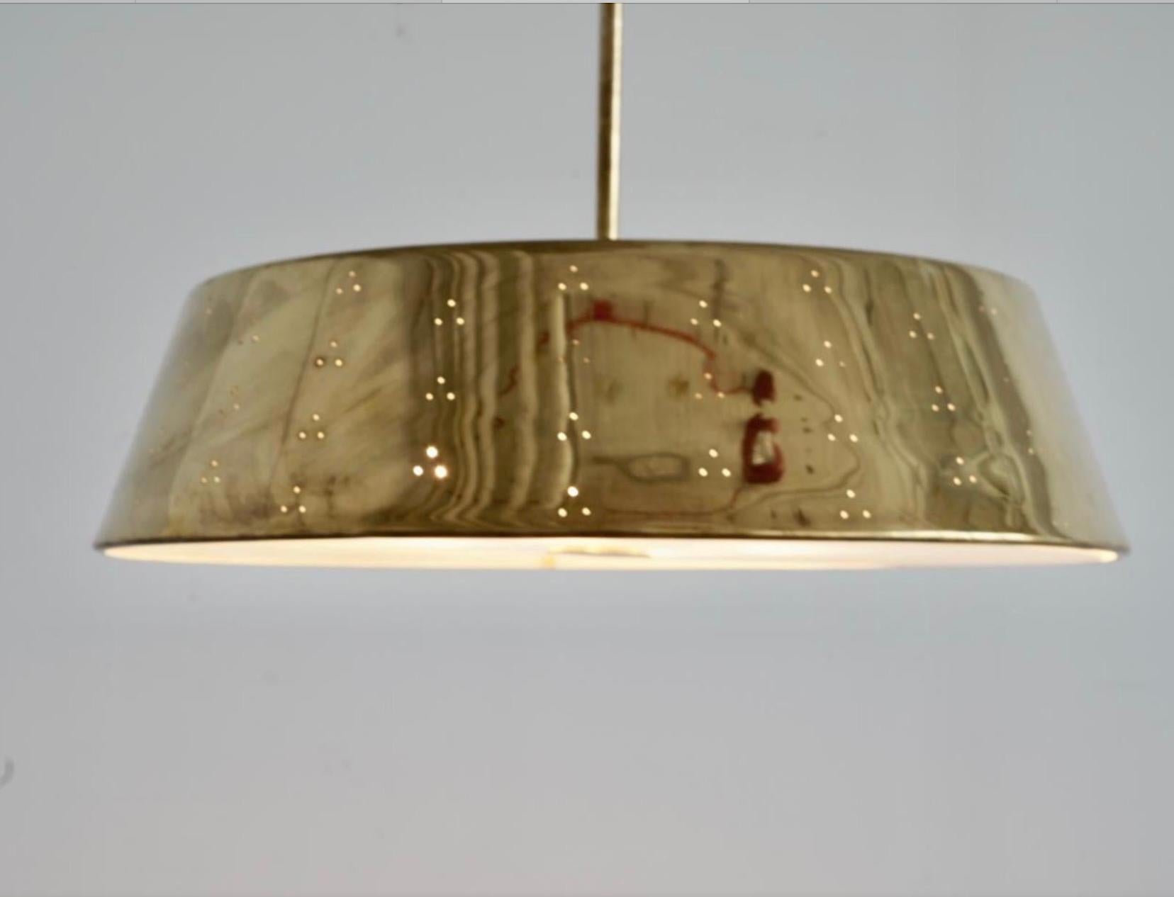 Una coppia di grandi lampade a sospensione disegnate da Paavo Tynell. Finlandia, circa 1950. Commissionato su misura per United Paper Mills, prodotto da Idman Oy Vilhonvuorenkatu. Ottone perforato lucido con diffusore in vetro smerigliato. (4) Prese