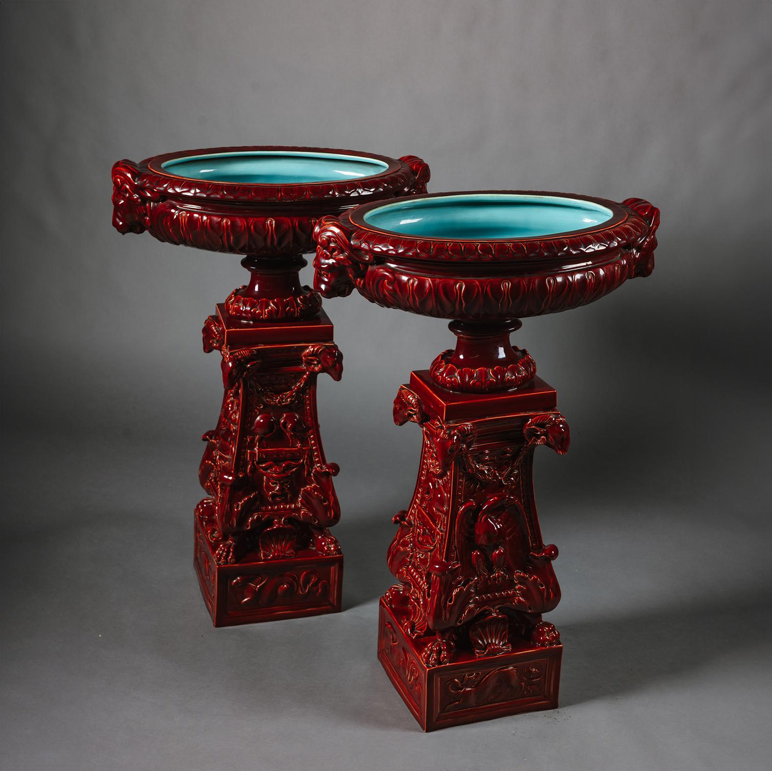 A Pair of Large Sarreguemines Majolica Sang de Boeuf Glazed Earthenware Jardinières On Pedestals.  

Each bowl with moulded leaf decoration, lion head handles and Bleu de Deck interior. On a baluster socle with square foot. The tapering pedestals