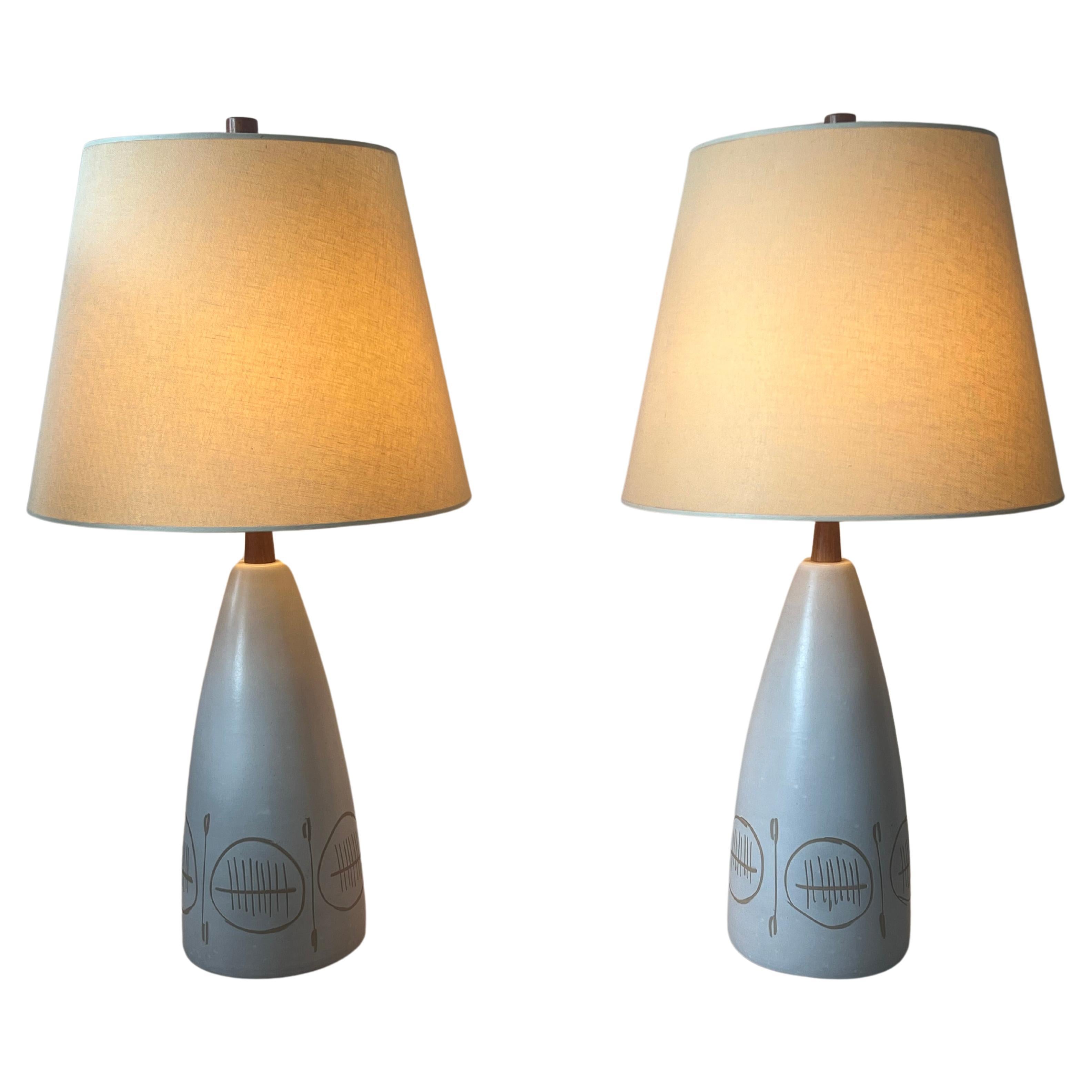 Iconic table lamp designed by the famed ceramicist duo Jane and Gordon Martz for Marshall Studios. Lamp features a conical, bullet shaped body with incised decorative motif. Lamp is completed with oak neck and finial. Lamp present mostly off white